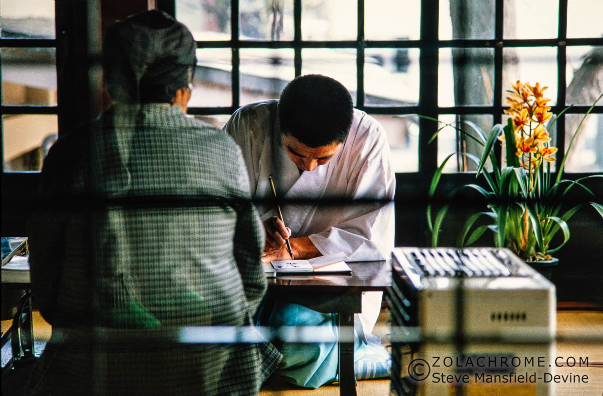 Priest writing in a temple seal book.