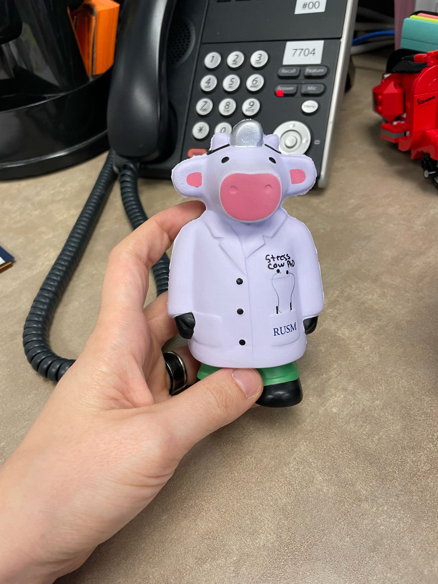 A stress toy shaped like a cow who practices medicine