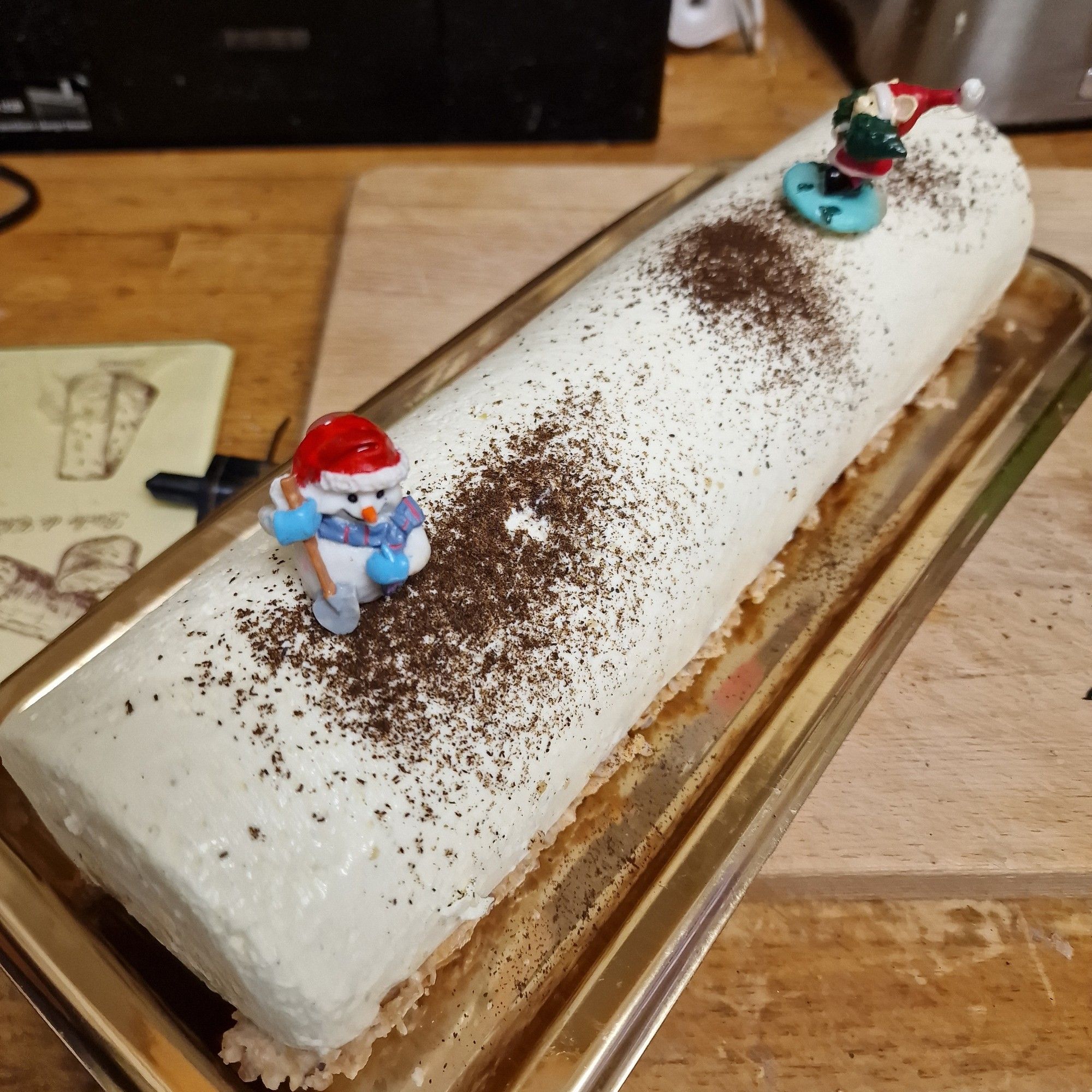 Buche vanille maison sur laquelle sont plantés un lutin de Noël et un père Noël