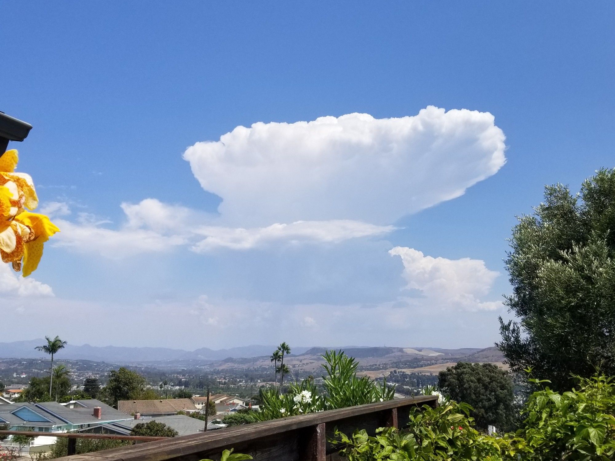 Thundercloud against a blue sky over a southern California landscape.