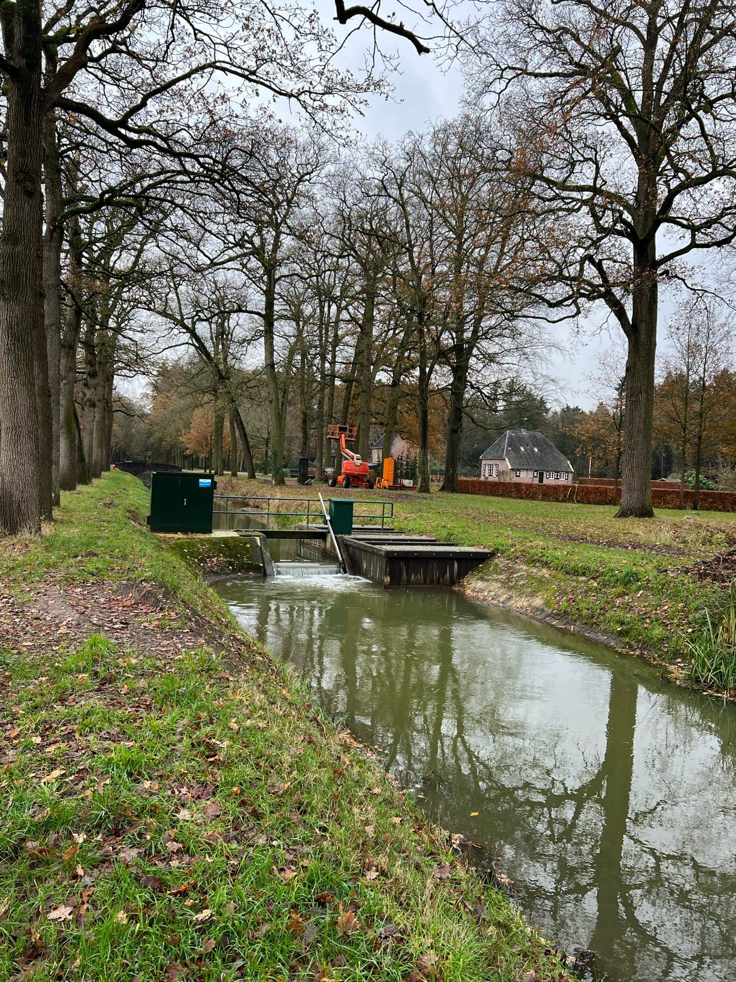 Een wetering met een sluisje in het midden. 
Aan weerskanten gras wallen.