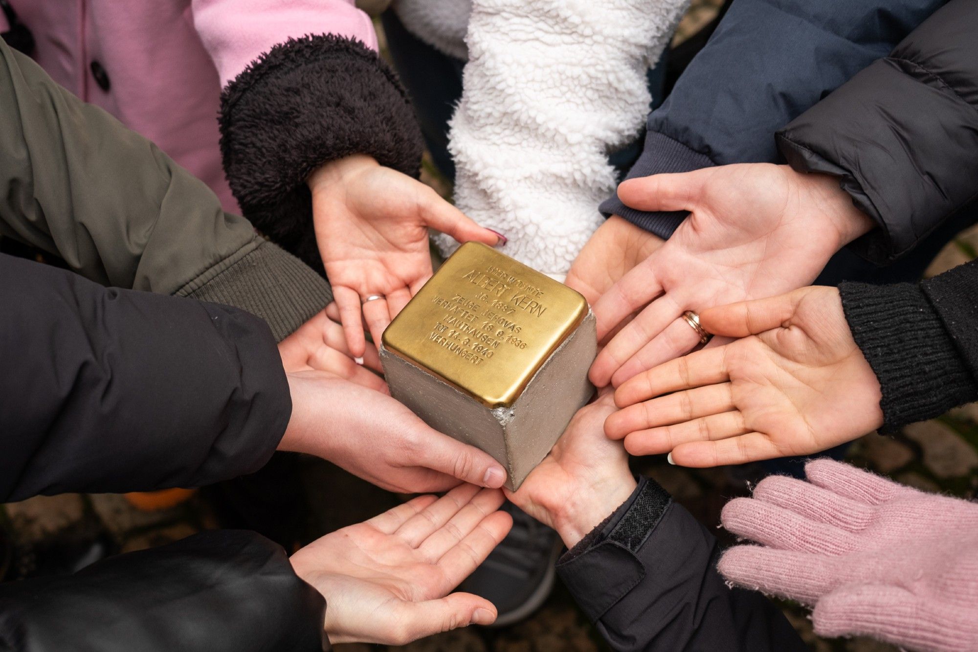 several people holding a #stolperstein