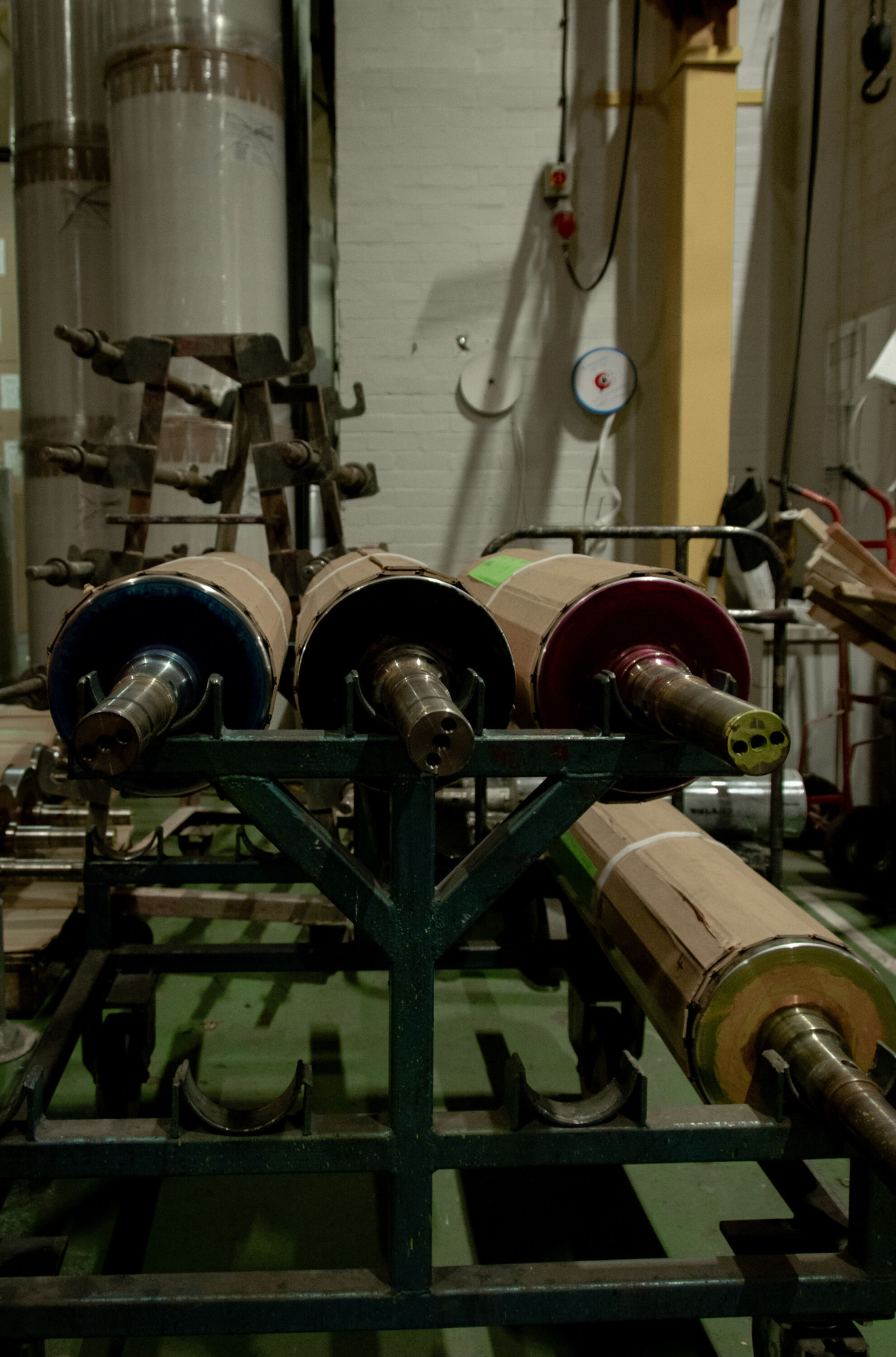 Ink rollers protected in cardboard stored in a metal frame.