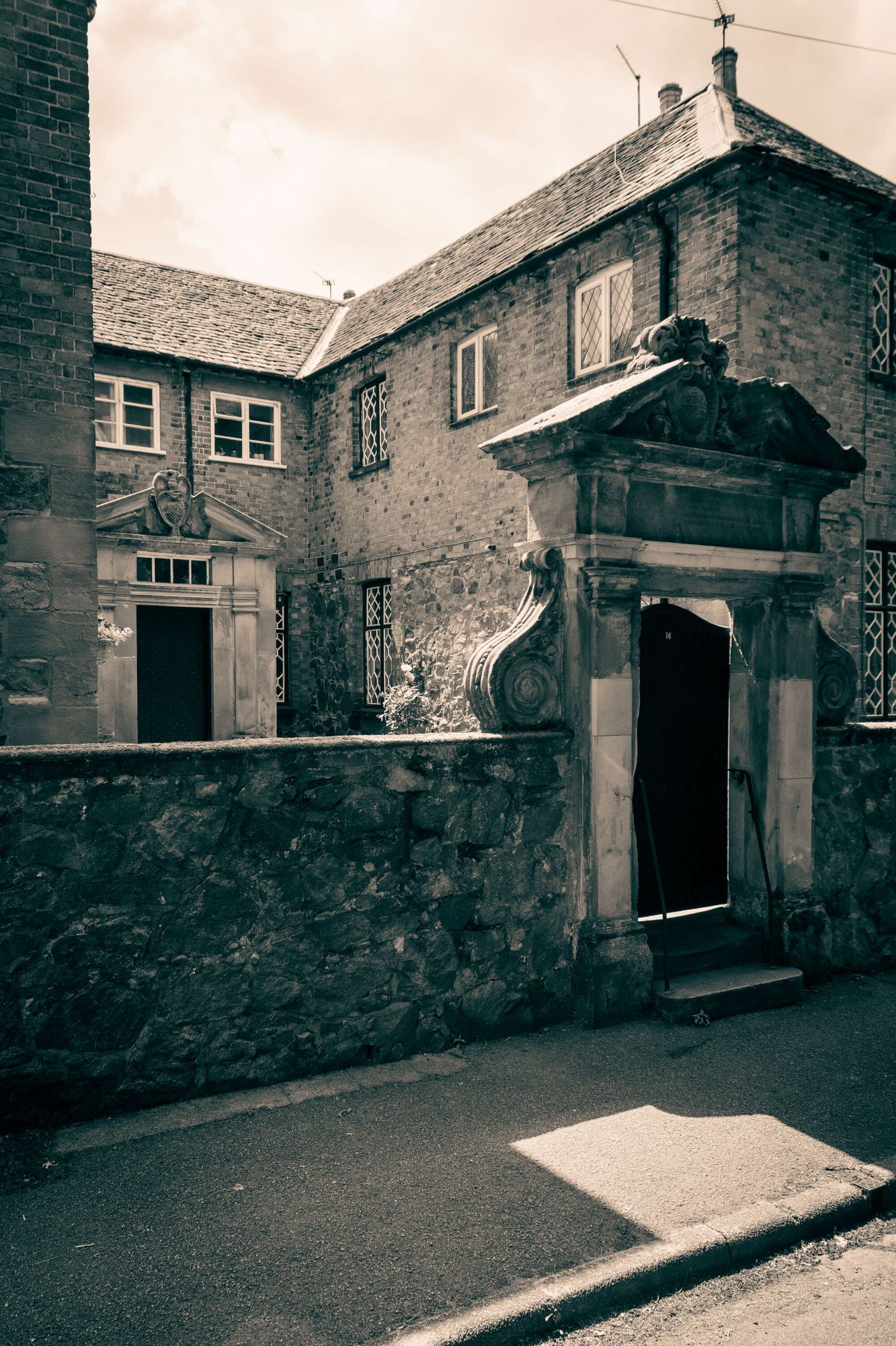 An old building behind a stone wall and gate.