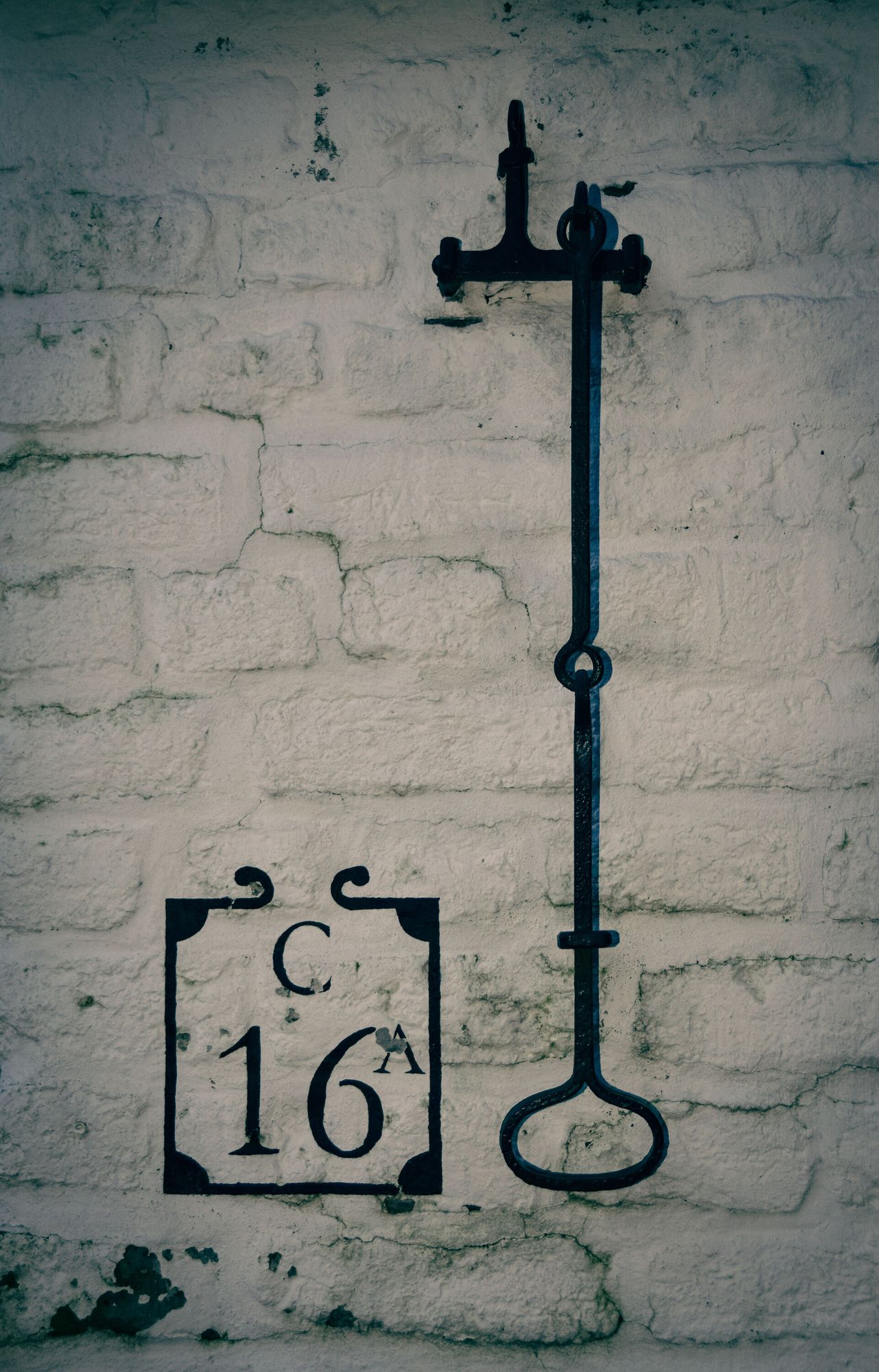 Bricks painted white; a painted house number, "C 16A", and an old-fashioned metal bell pull.