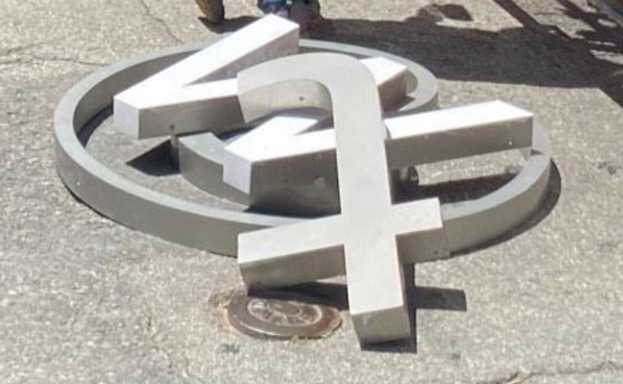 A photo of the letters "@tw" lying piled on top of each other on a San Francisco sidewalk.