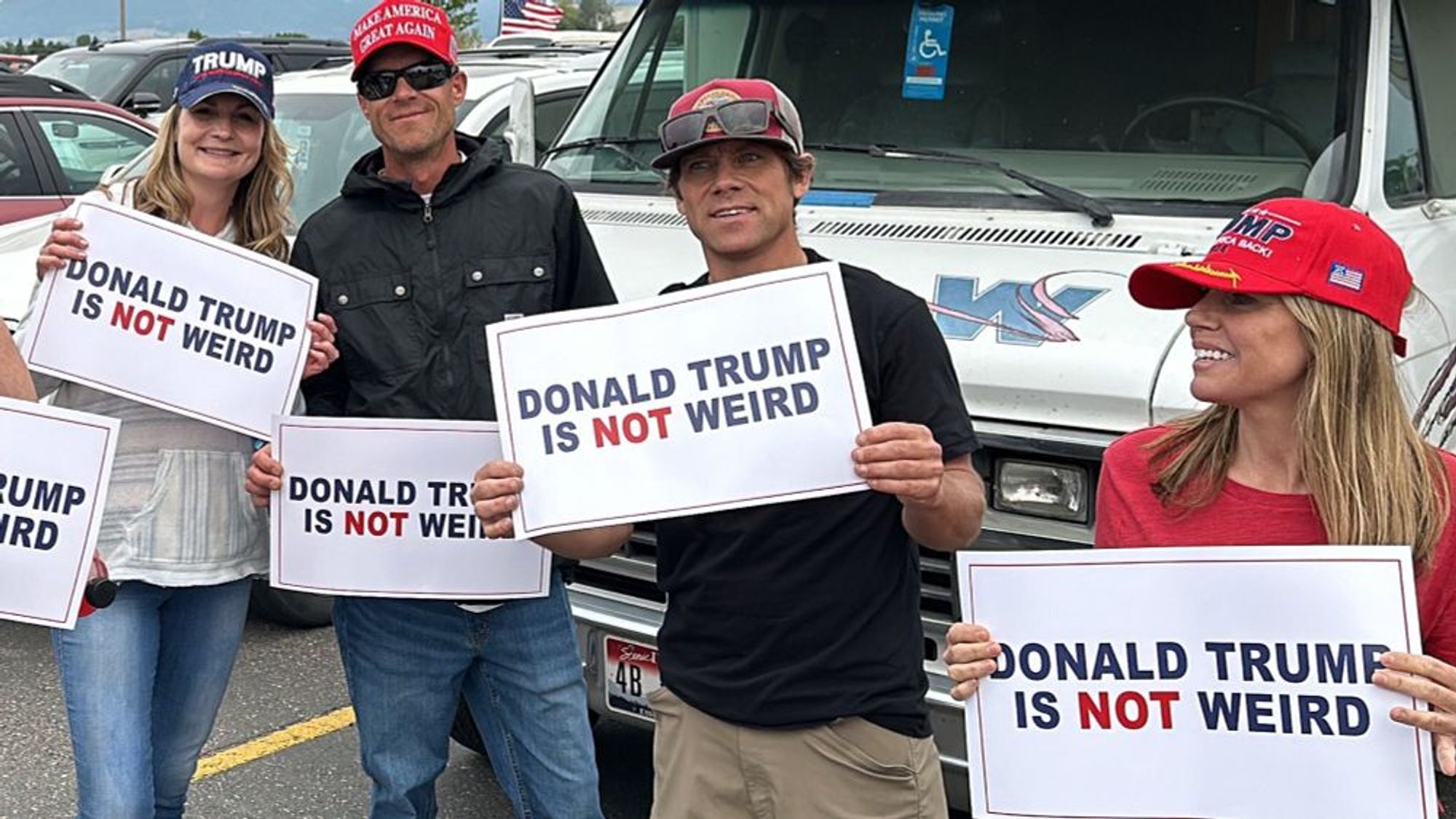 A group of people wearing Trump hats holding signs saying:

DONALD TRUMP IS NOT WEIRD