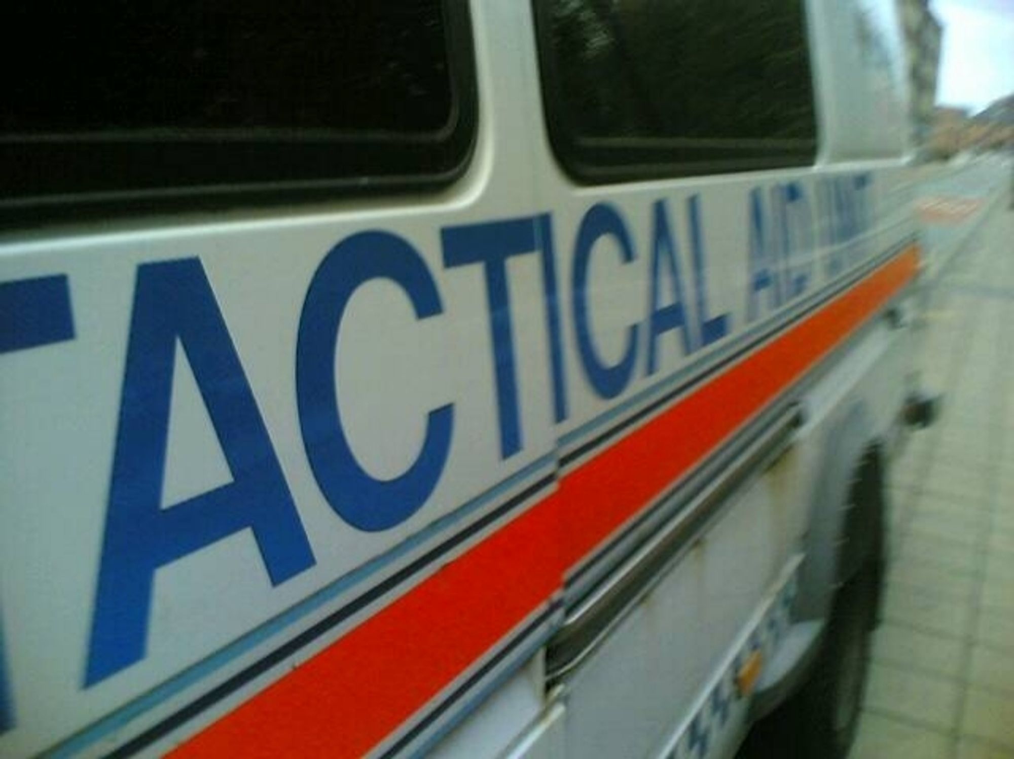 The side of a Greater Manchester Police van, with the words Tactical Aid Unit in blue capital letters