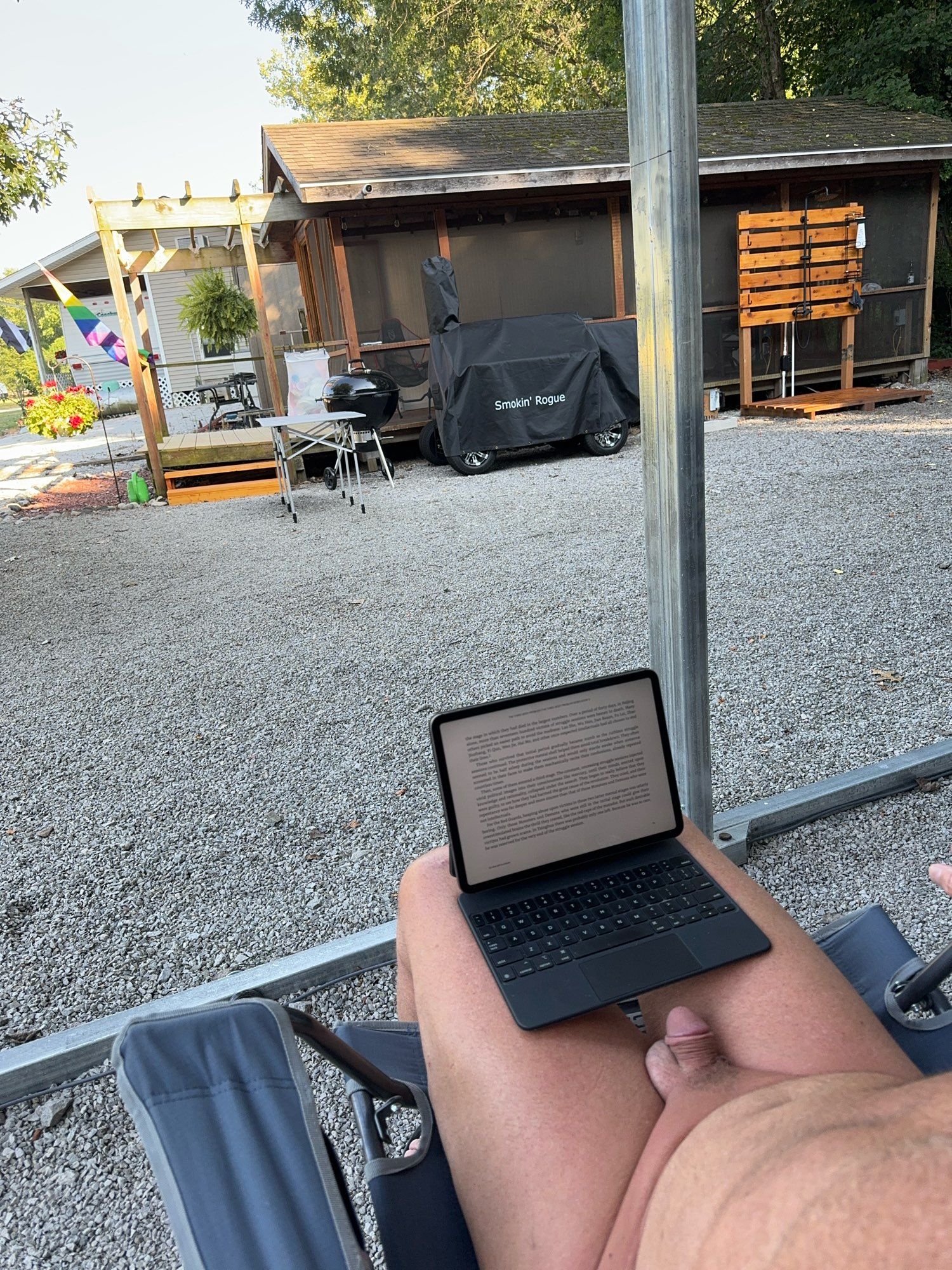 Nude male relaxing and reading in his camp site.