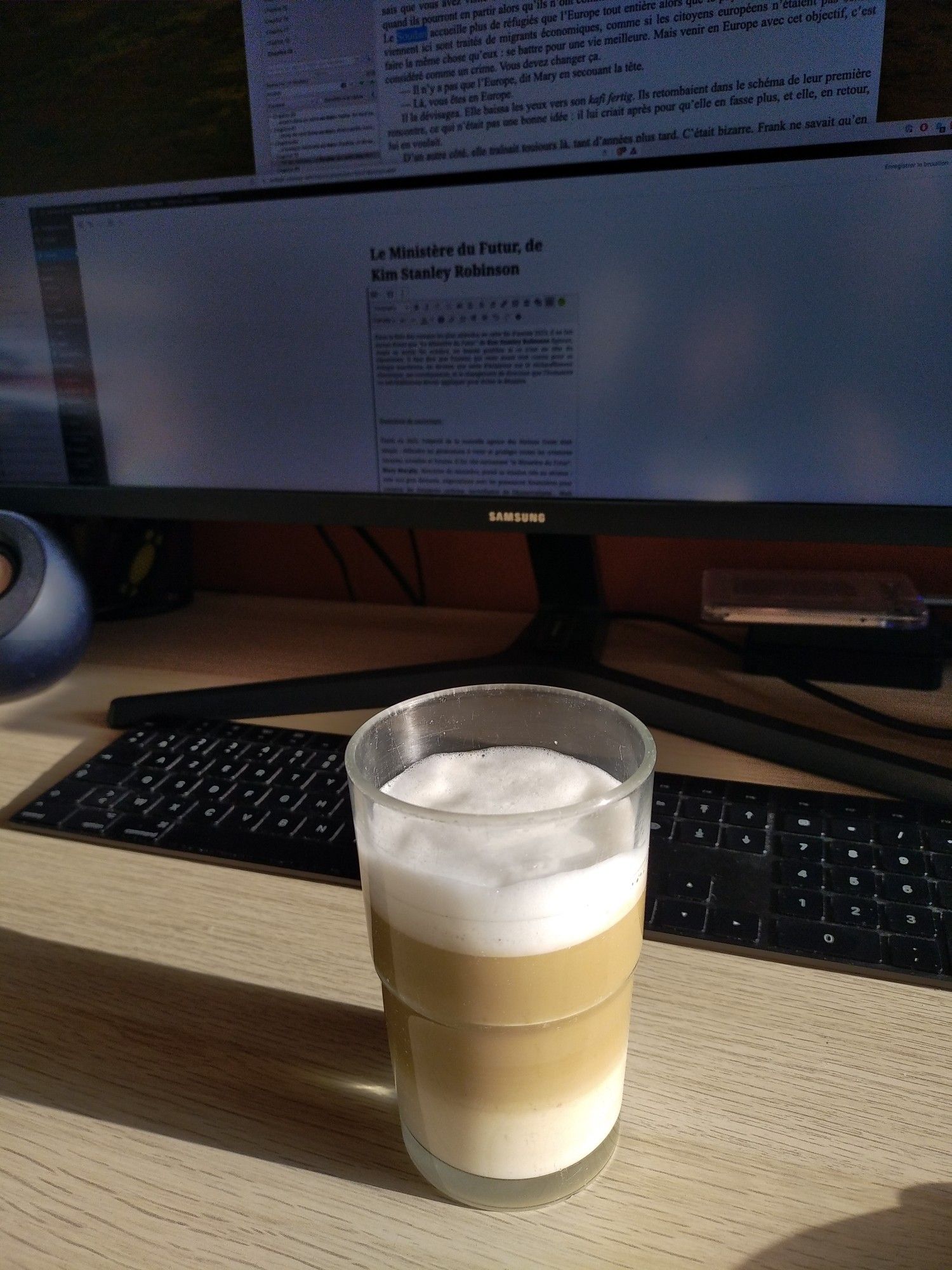 Un latte macchiato devant mon ordinateur. Écriture en cours de la chronique du roman "Le Ministère du Futur" de Kim Stanley Robinson.