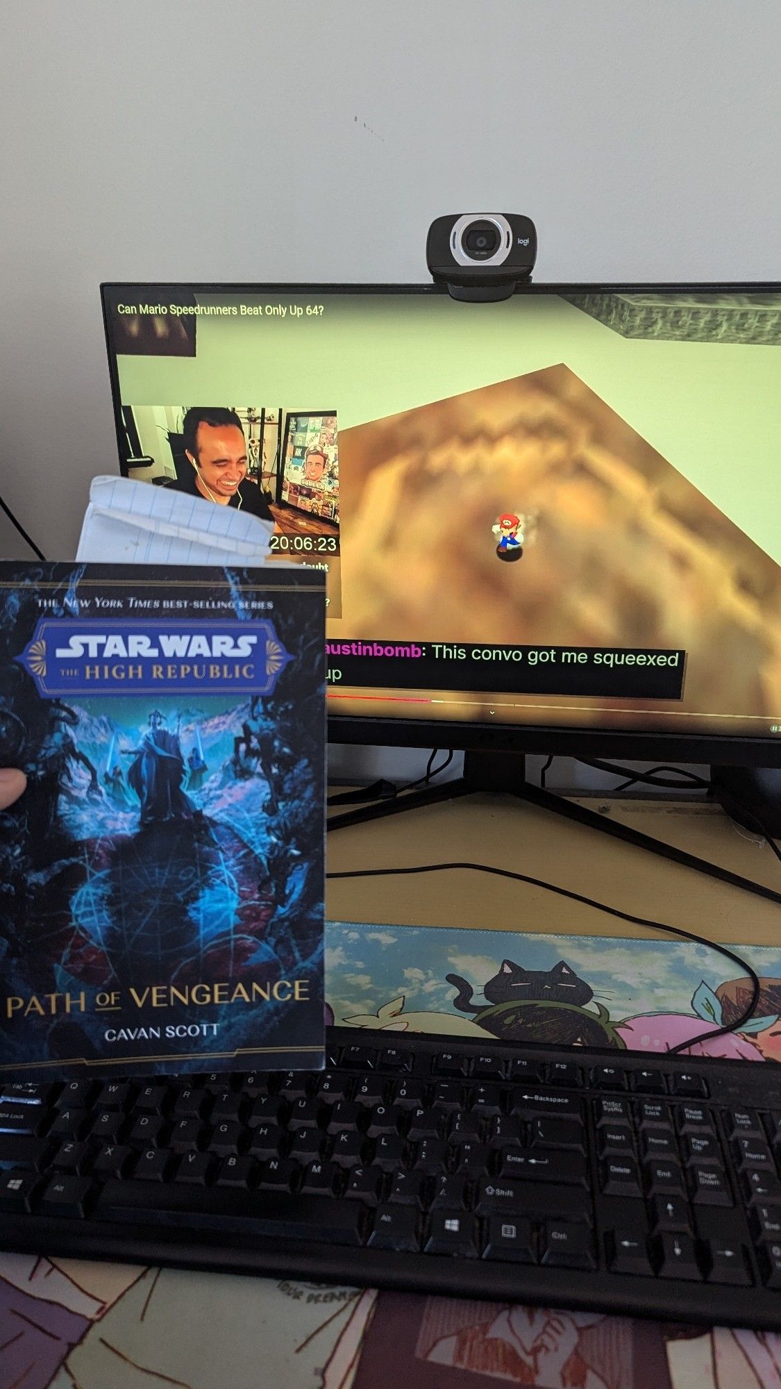 Me holding up a copy of Star Wars: The High Republic: Path of Vengeance in front of my computer that has a video of Squeex and a caption that says "This convo got me squeexed up"