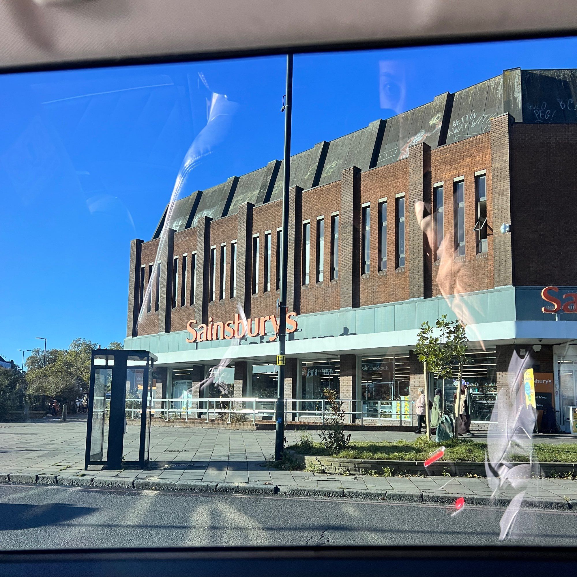 Sainsbury with big windows on the ground floor and a paved area out front