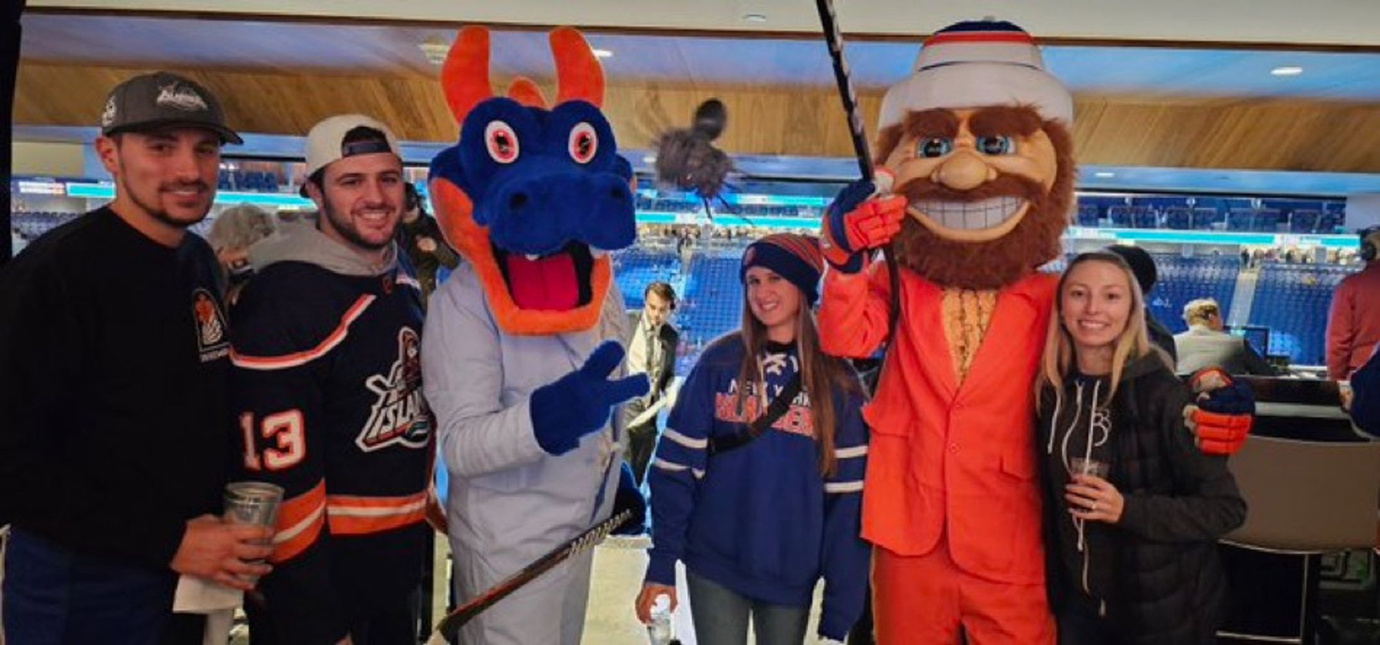 Islanders mascots Sparky the Dragon and Nyisles pose with fans. Sparky and Nyisles are wearing tuxes like Harry and Lloyd from the movie Dumb and Dumber.