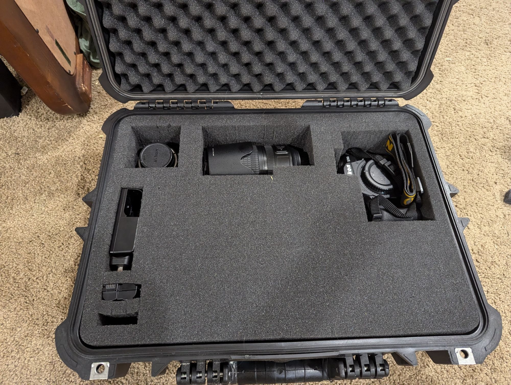 A knockoff pelican case filled with one camera, two lenses, a battery charger, and a battery.