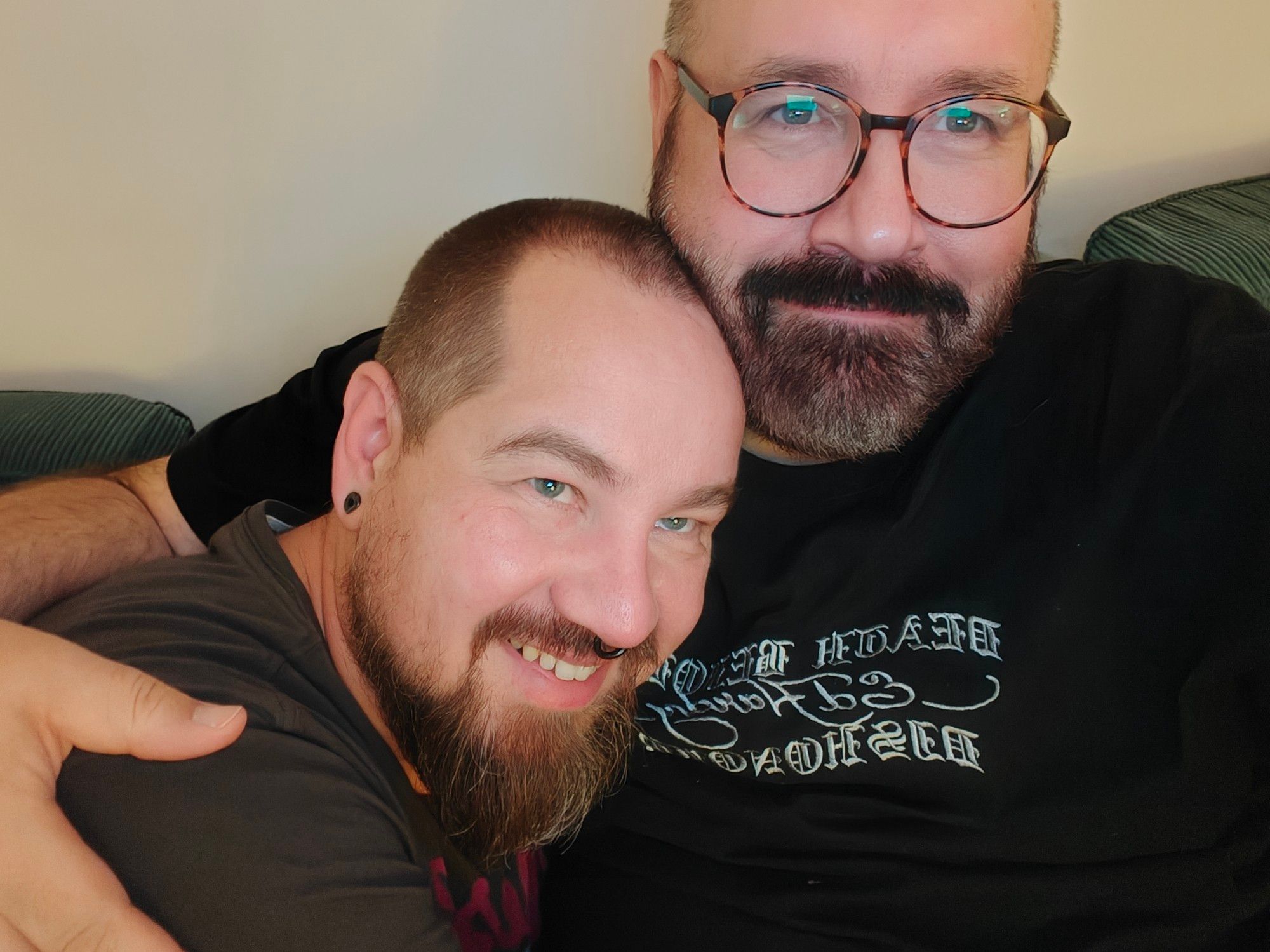 A photo of me, a balding bear man with beard and glasses. I'm cuddling another bearish man with a longer beard and more hair. We're very happy.