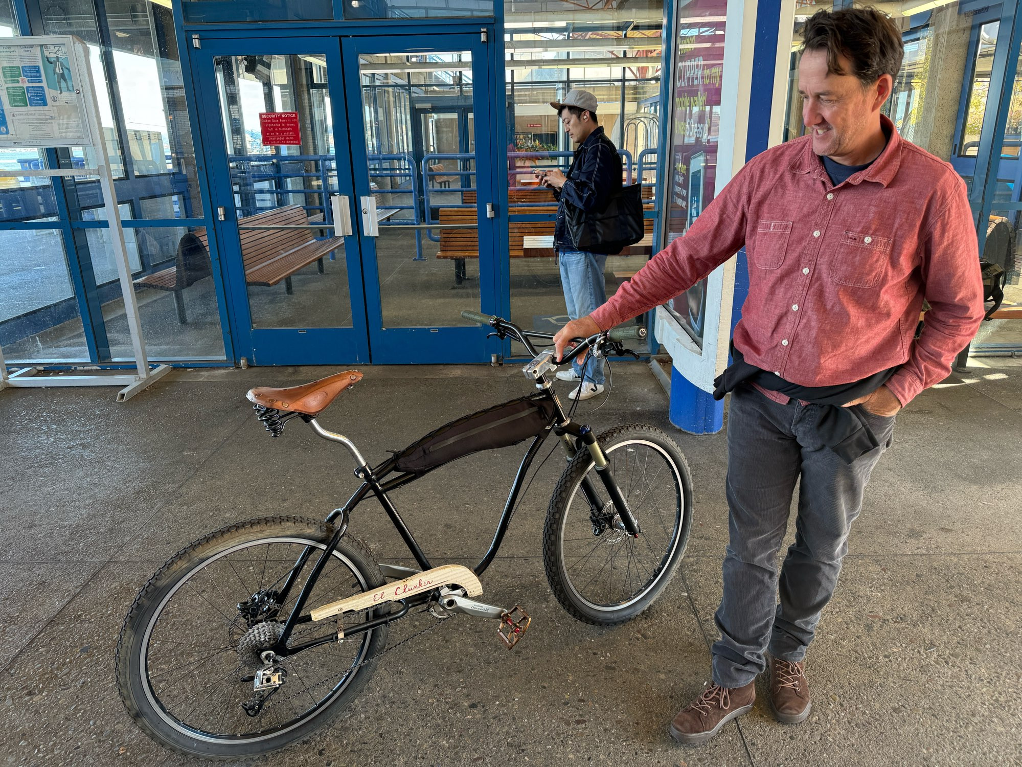 a black pre-war Schwinn Flier frame modified with a disc brake tab and with modern threadless headset and outboard-bearing bottom bracket. it has a custom framebag between the double top tubes, a 1x9 derailleur drivetrain, hydraulic desk brakes, a ~100mm travel suspension fork, a sick BMX stem, and Surly Sunrise handlebars.