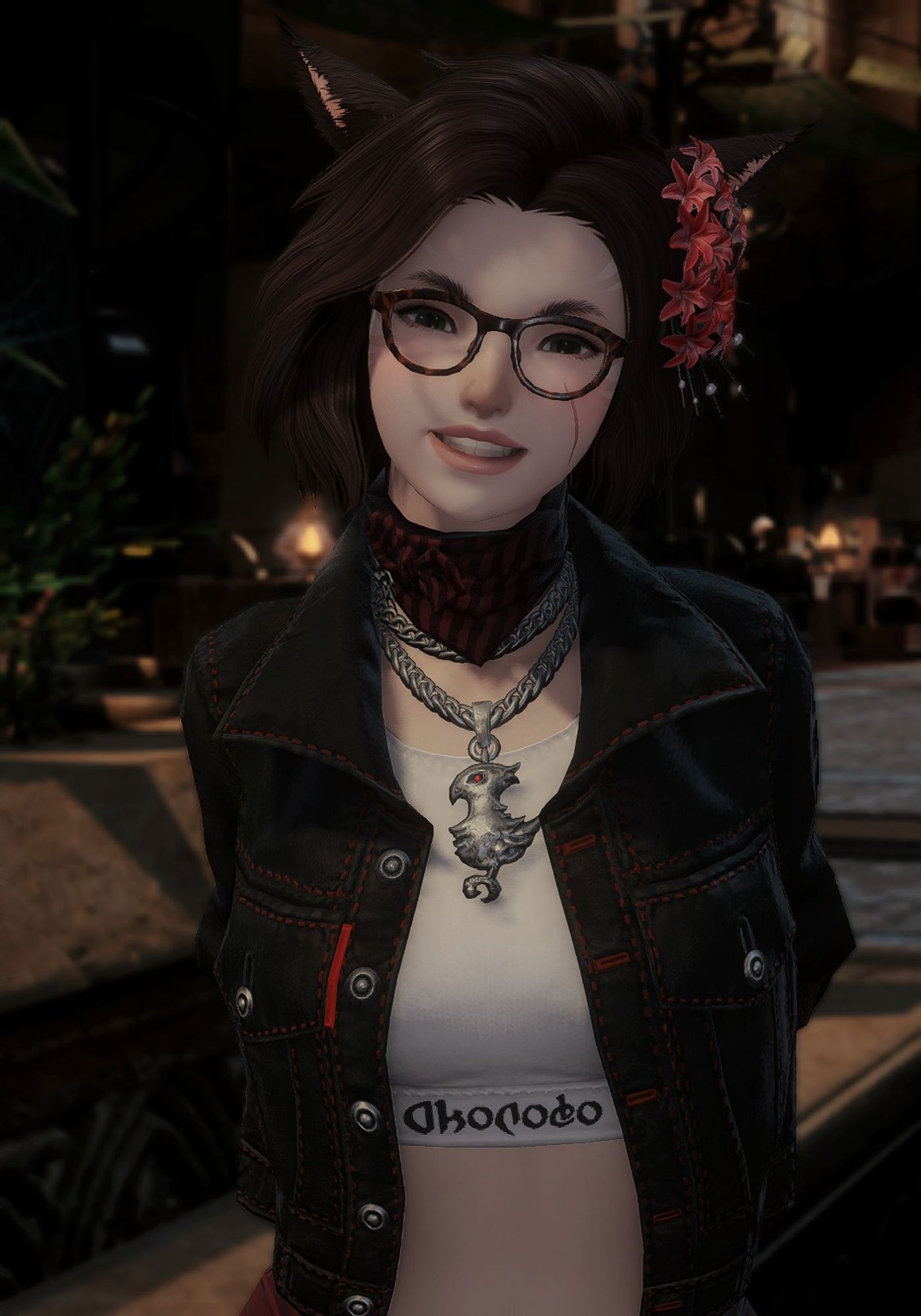 Taja, a brunette miqo'te woman, smiles happily into the camera. she wears a cropped white shirt with a black jacket with red accents overtop, a red and black scarf necklace, a chain chocobo necklace, red flowers in her hair, and brown tortoiseshell glasses. her arms are clasped behind her back.