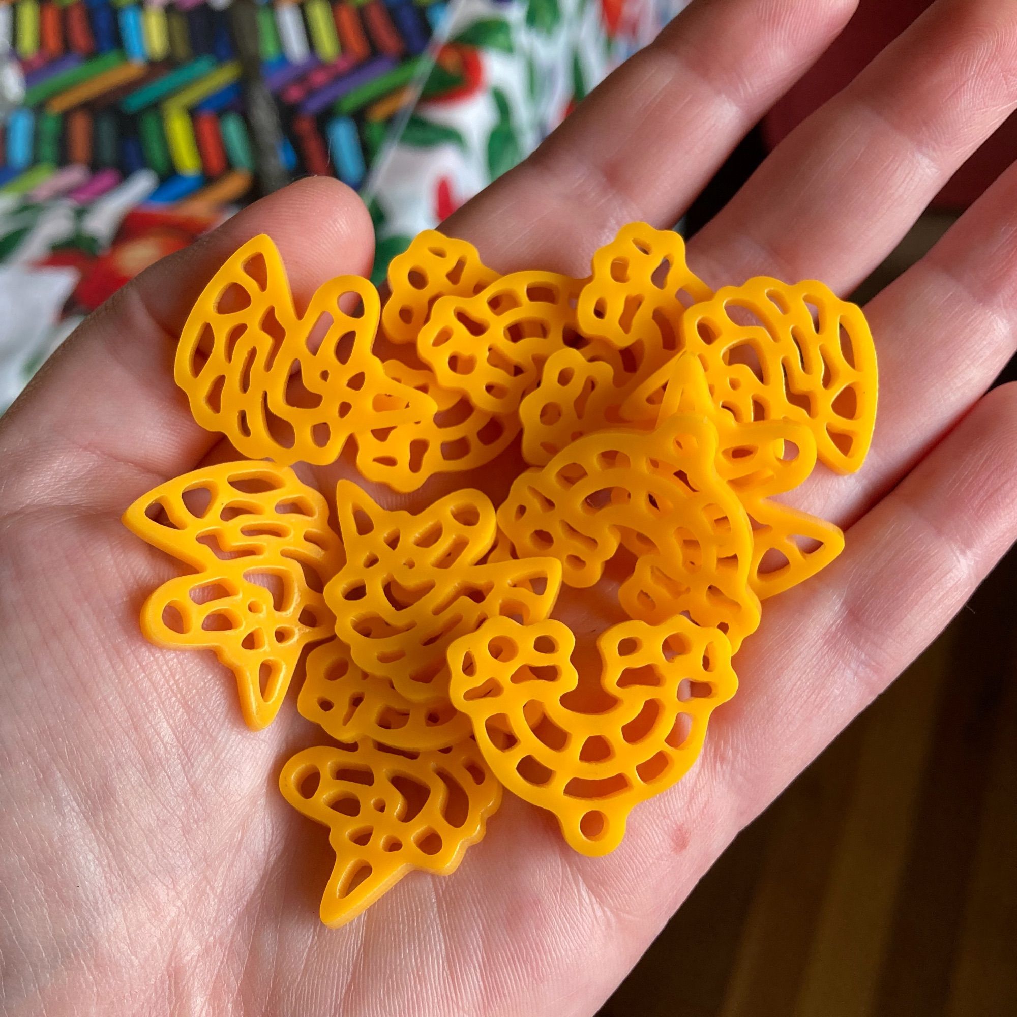 a handful of laser cut acrylic mac and cheese rainbows and unicorns, waiting to become earrings and/or keychains