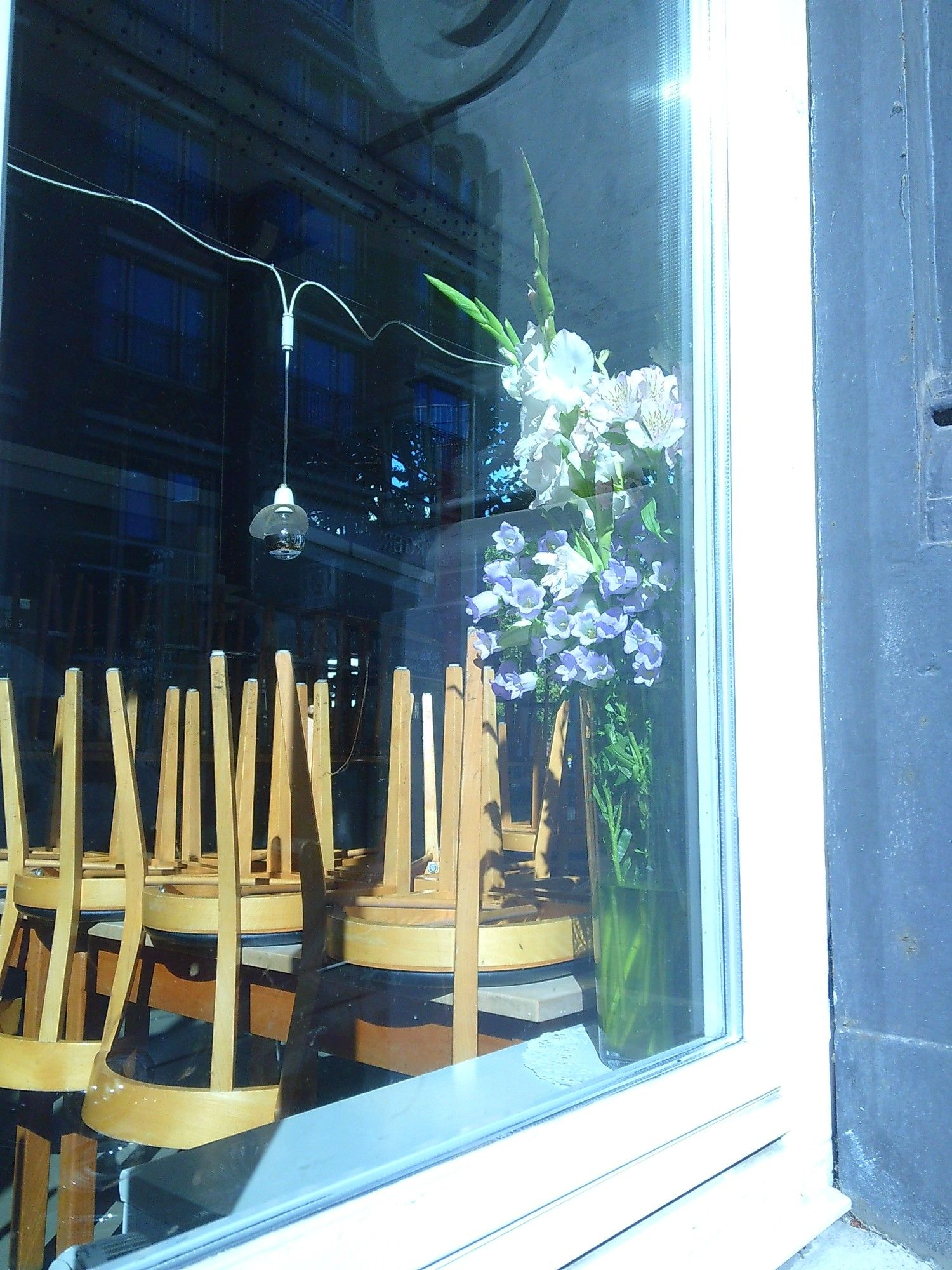 Schaufenster mit hochgestellten Stühlen und einen Blumenstrauß an der Seite