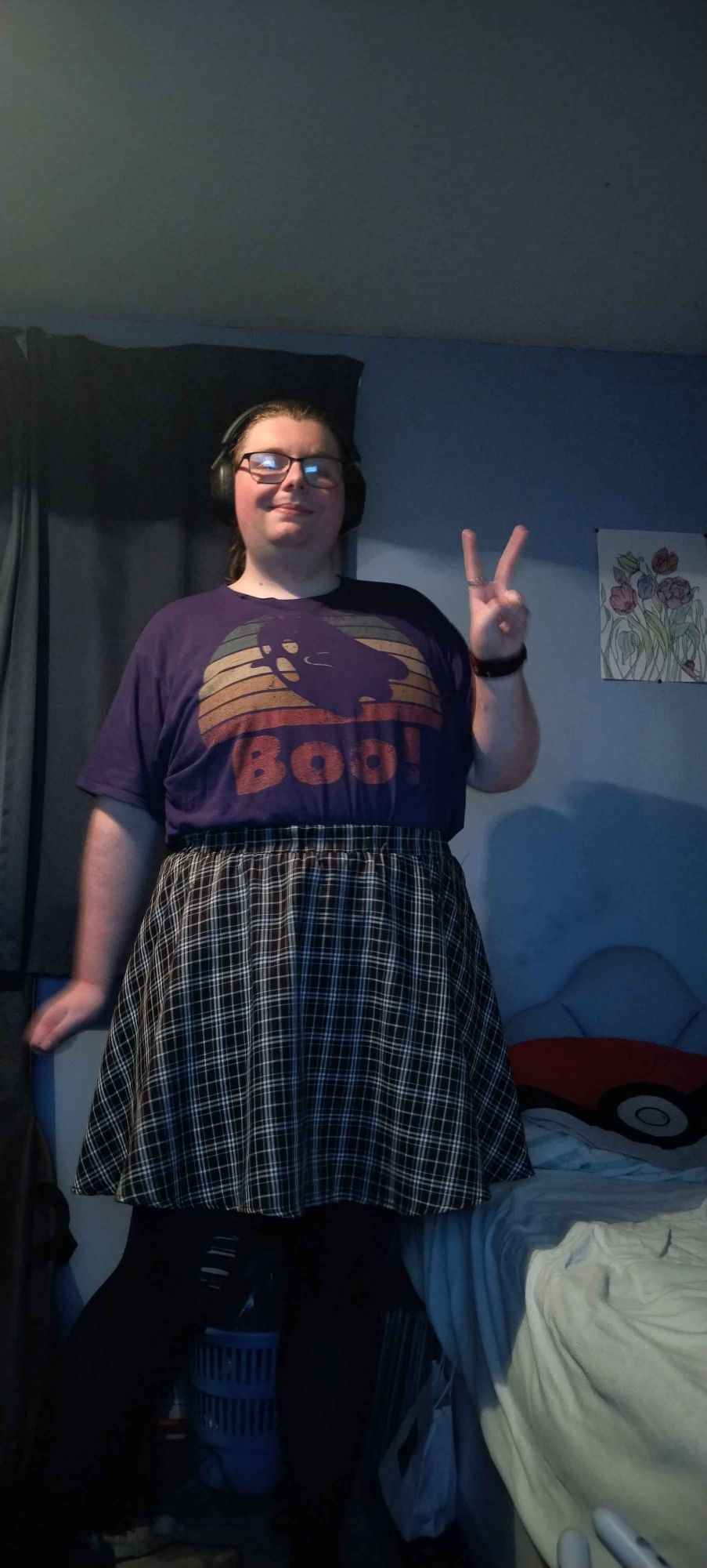 Me Wearing A Purple T Shirt With A Ghost And The Word BOO, A Black And White Check Knee Length Skirt, And Black Tights.