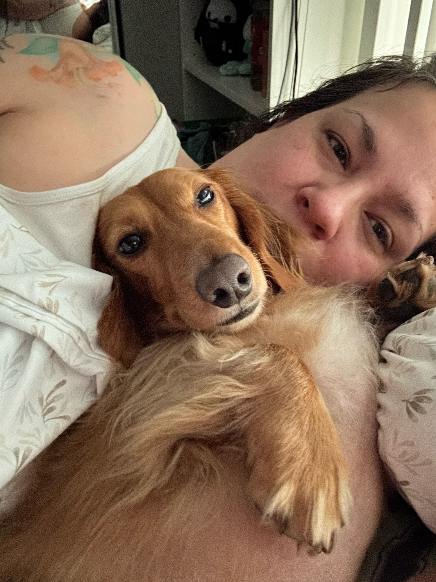 Different angle of me and Jack. Jack is laying against me with his head in my neck looking at the phone camera. His ear is covering my mouth and I am NOT holding him. He is bare chested and a facing belly up, one floofy-toed foot visible on his chest, the other is up by my face.