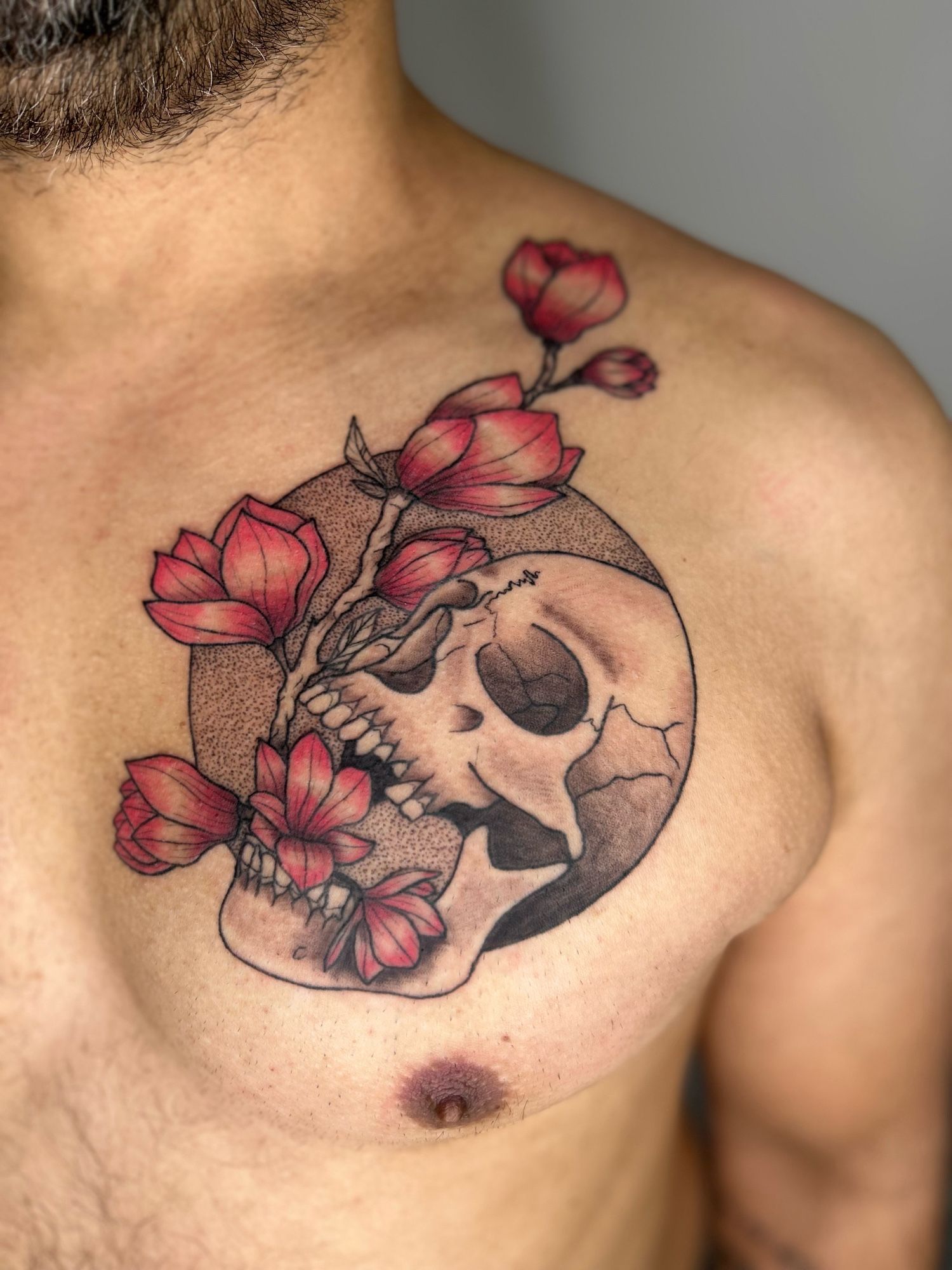 A man’s chest with a tattoo of a skull with flowers growing out of its mouth