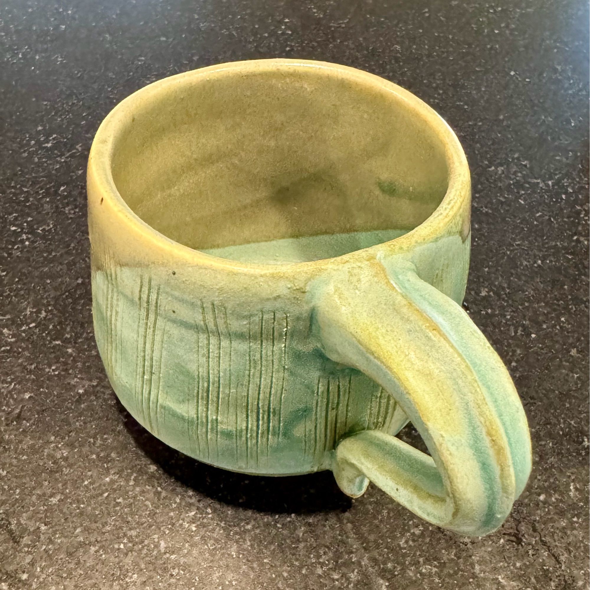 The same mug, from a different angle, showing the diagonal lines of the glaze inside the mug, and the texture of the handle (it has a ridge down the center).