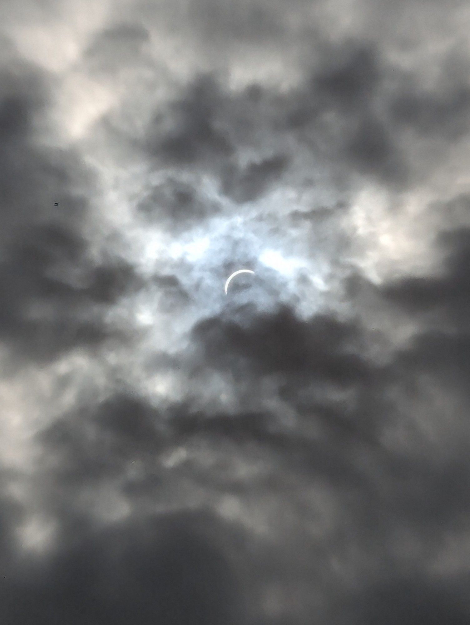 The sun is being eclipsed by the moon behind dark clouds