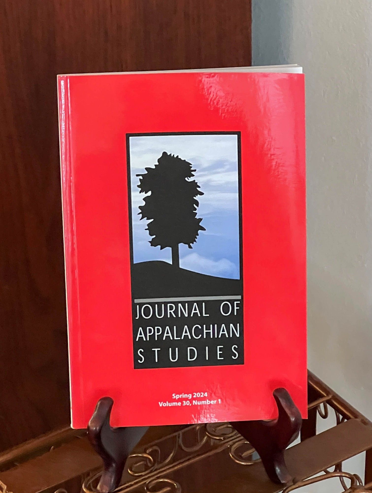 Cover of Journal of Appalachian Studies, Volume 30, Number 1, Spring 2024
Silhouette of a tree on a hill in front of a cloudy sky, red background