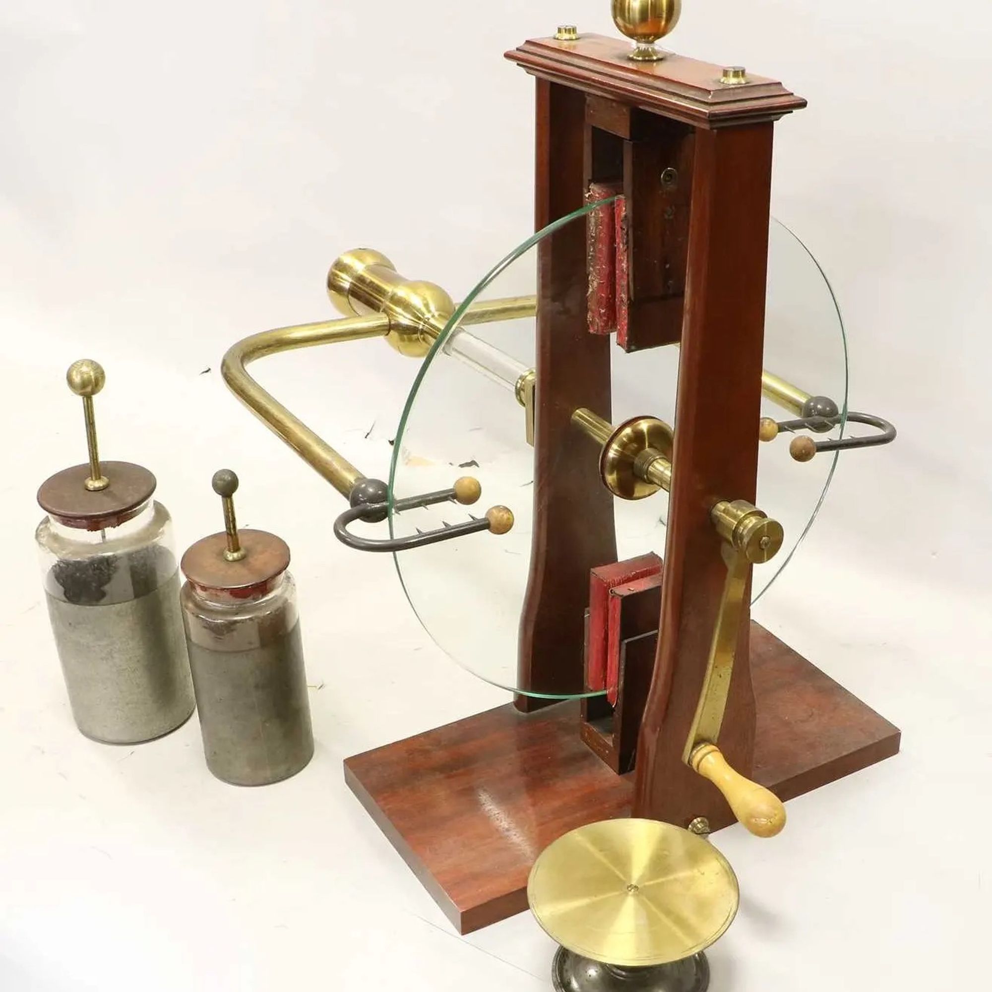 Photo of a Ramsden generator assembled and with two Leyden jars. The Ramsden is a tribo carging device with a glass disc turned by handle. You can see the charge collectors, U shapes around the glass with spikes.