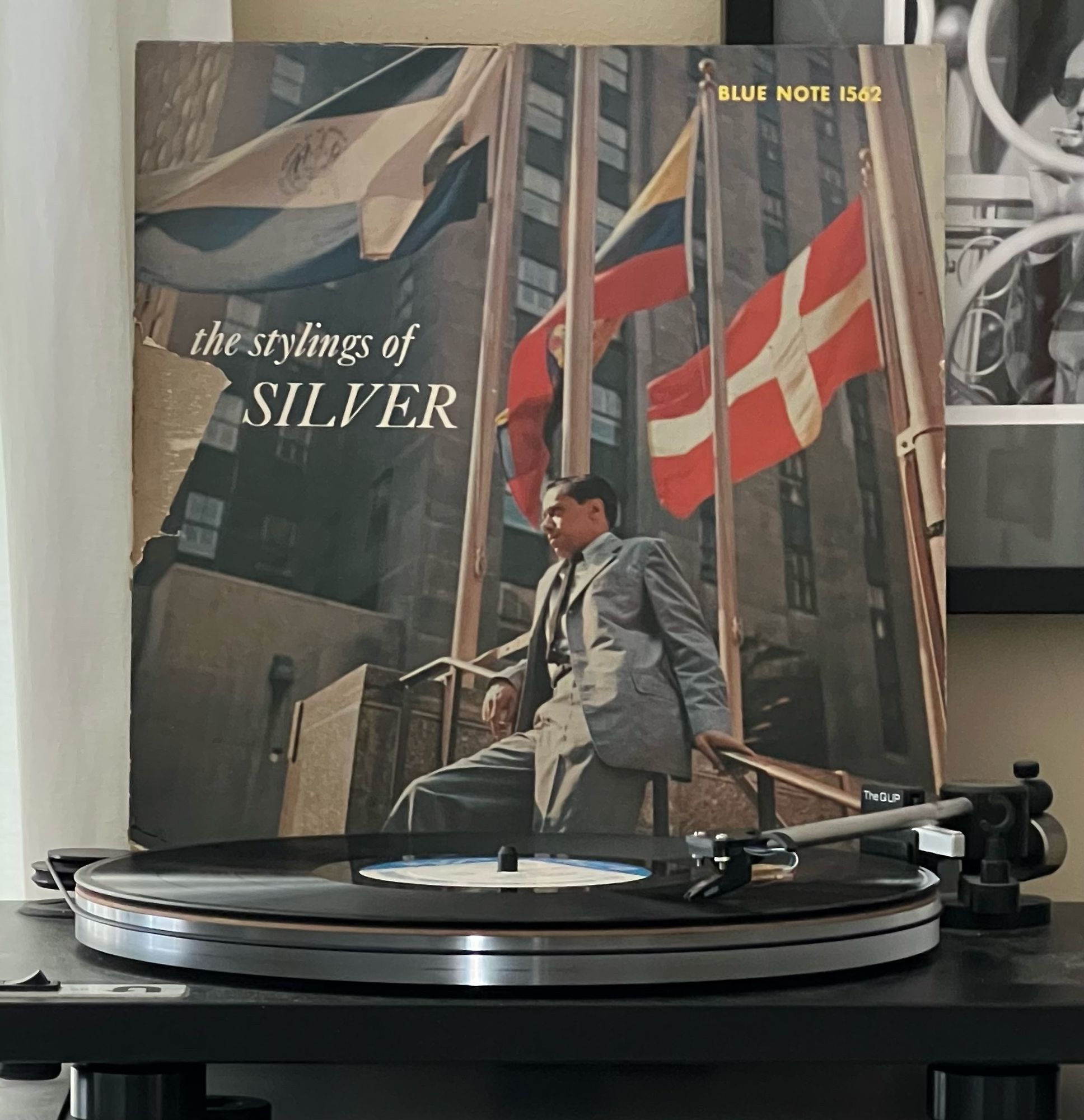 The Stylings of Silver LP, sleeve missing a chunk of surface that made it affordable. Horace is pictured leaning on a stair rail against a backdrop of a building and international flags on flagpoles, as happens