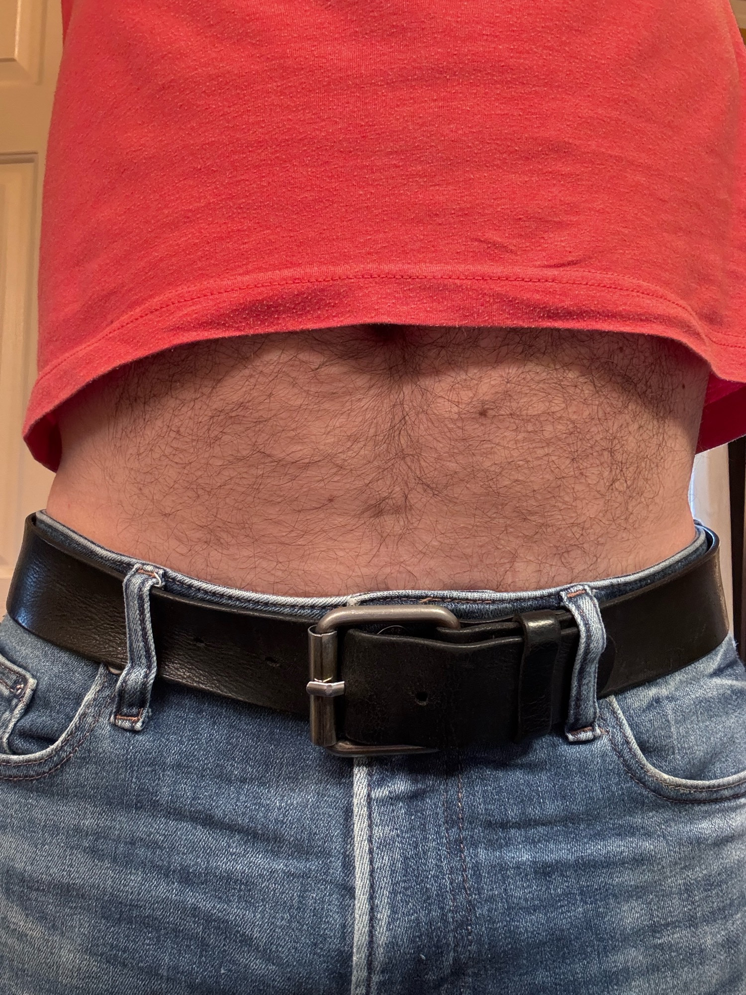 A close-up picture of a man’s belly being exposed when his shirt lifts up