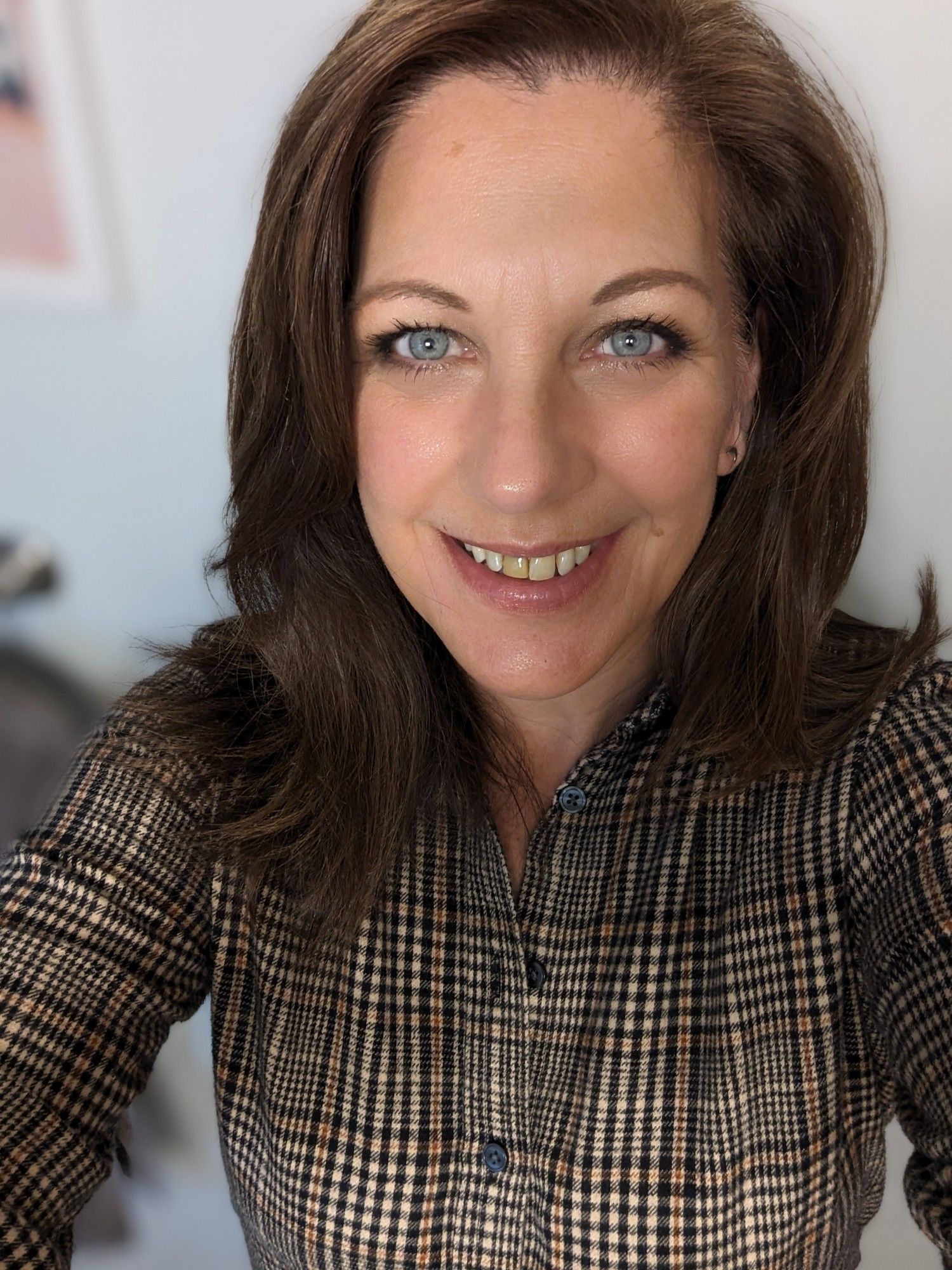 A woman with dark brown hair in a brown Glen plaid shirt, celebrating PLAIDURDAY, which is a day to wear and celebrate the best color: Plaid