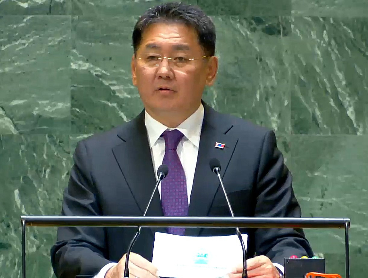 Screenshot of video recording of Pres. Khurelsukh addressing the UN General Assembly. He is standing at the lectern, reading from a piece of paper, but looking at the audience at the moment that I took this screenshot. He's wearing a dark blue suit, white shirt and a patterened subtly purplish tie as well as a Mongolian flag lapel pin.