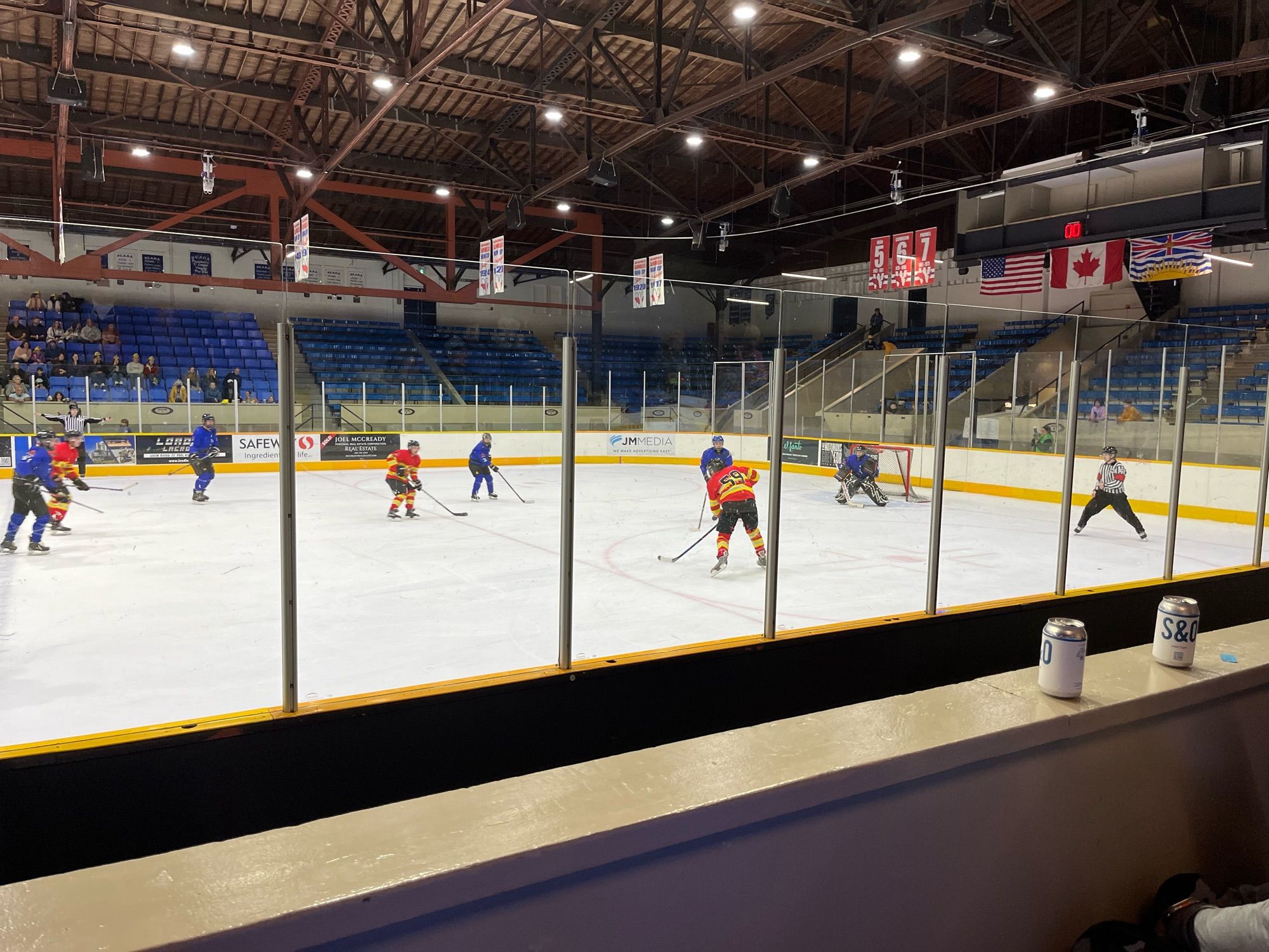 Charity hockey game between New West Police in blue and New West Fire in red. A New West Fire player is taking a shot on goal.