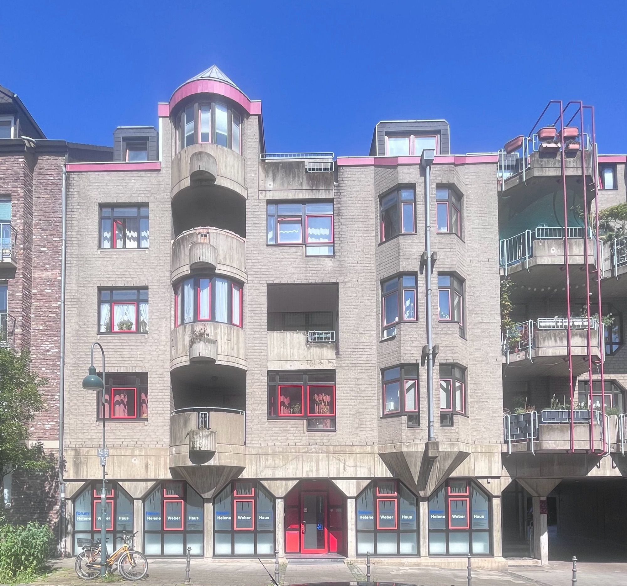 A concrete housing and office block with red accents