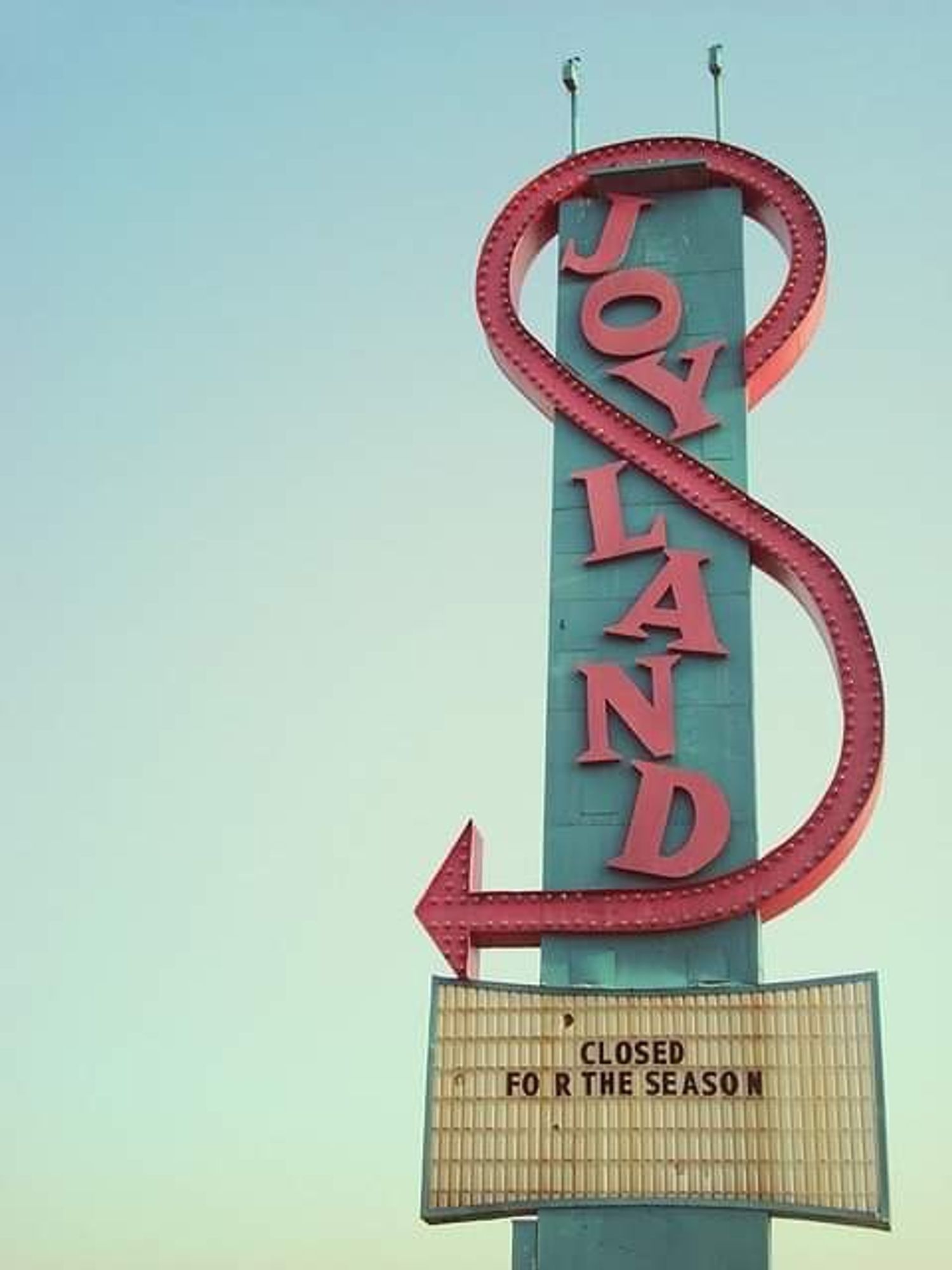 Photo of an amusement park sign saying: Joyland. 
The notice immediately below it says: Closed for the season.