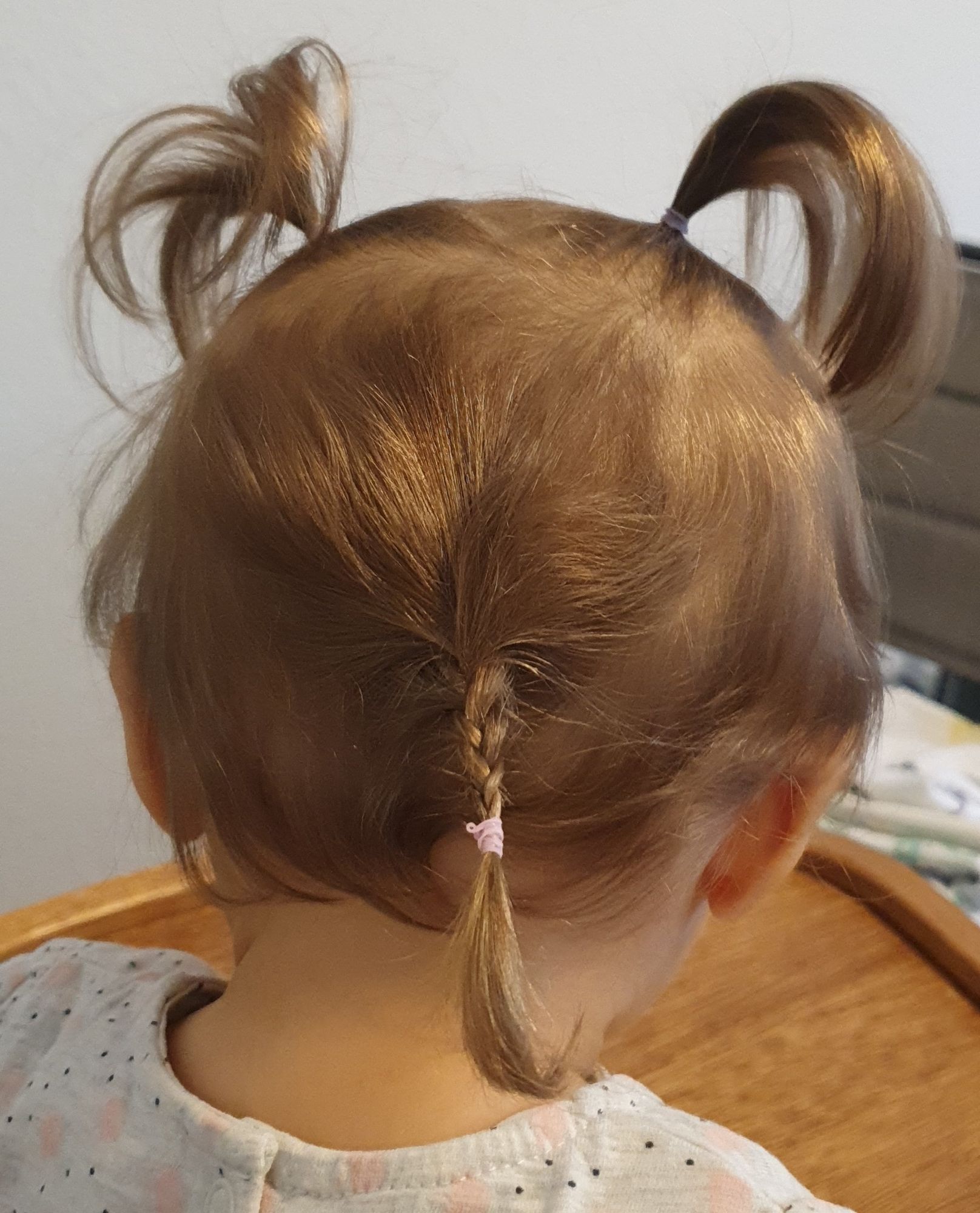 Babykopf von hinten mit 2 kleinen Palmen vom oberen Deckhaar und die hinteren Haare zu einem winzigen dünnen Zopf geflochten