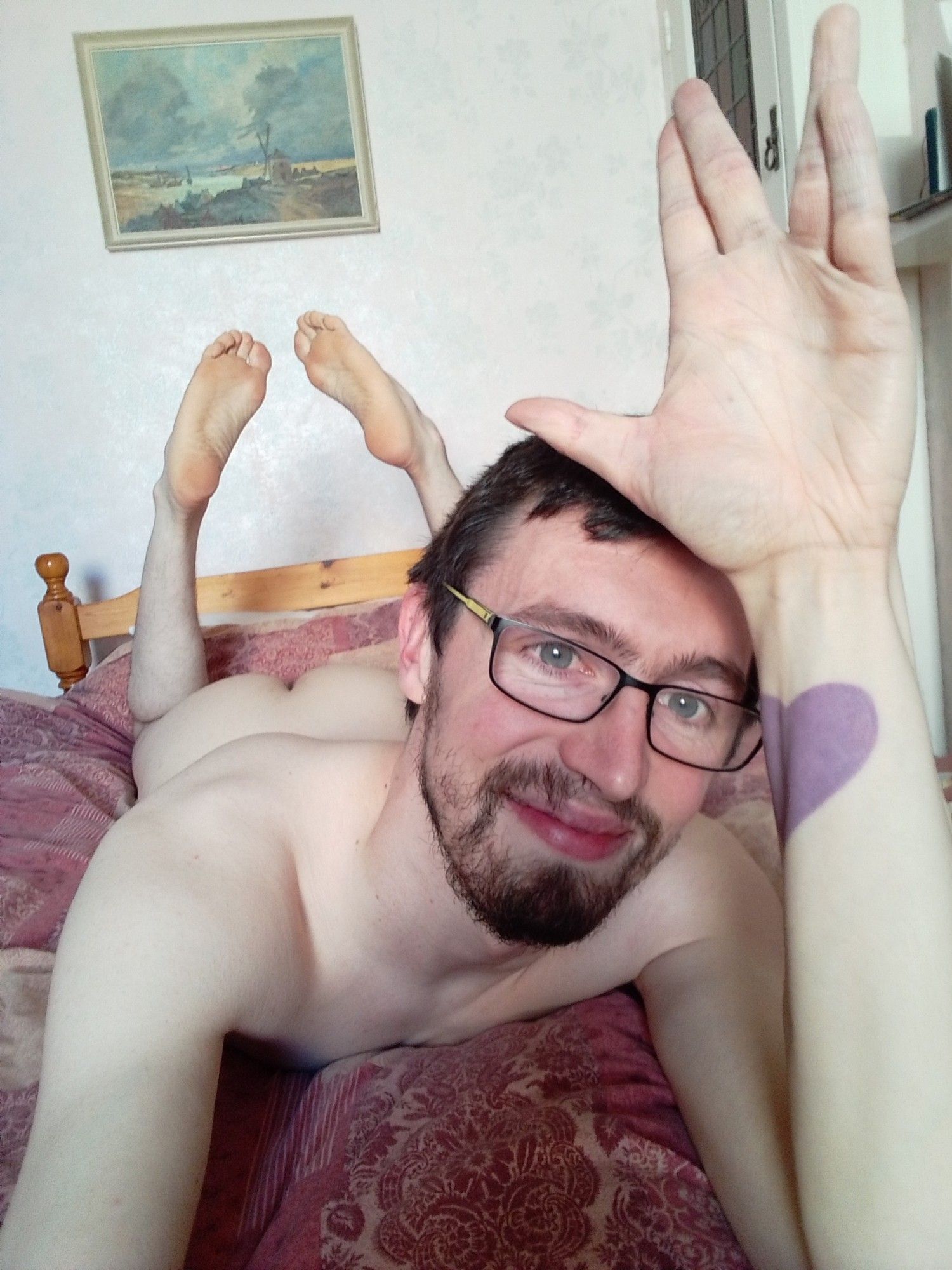 Me lying naked on my bed, ass up, soles in the air, hand raised a little above my head in a Vulcan salute, smiling