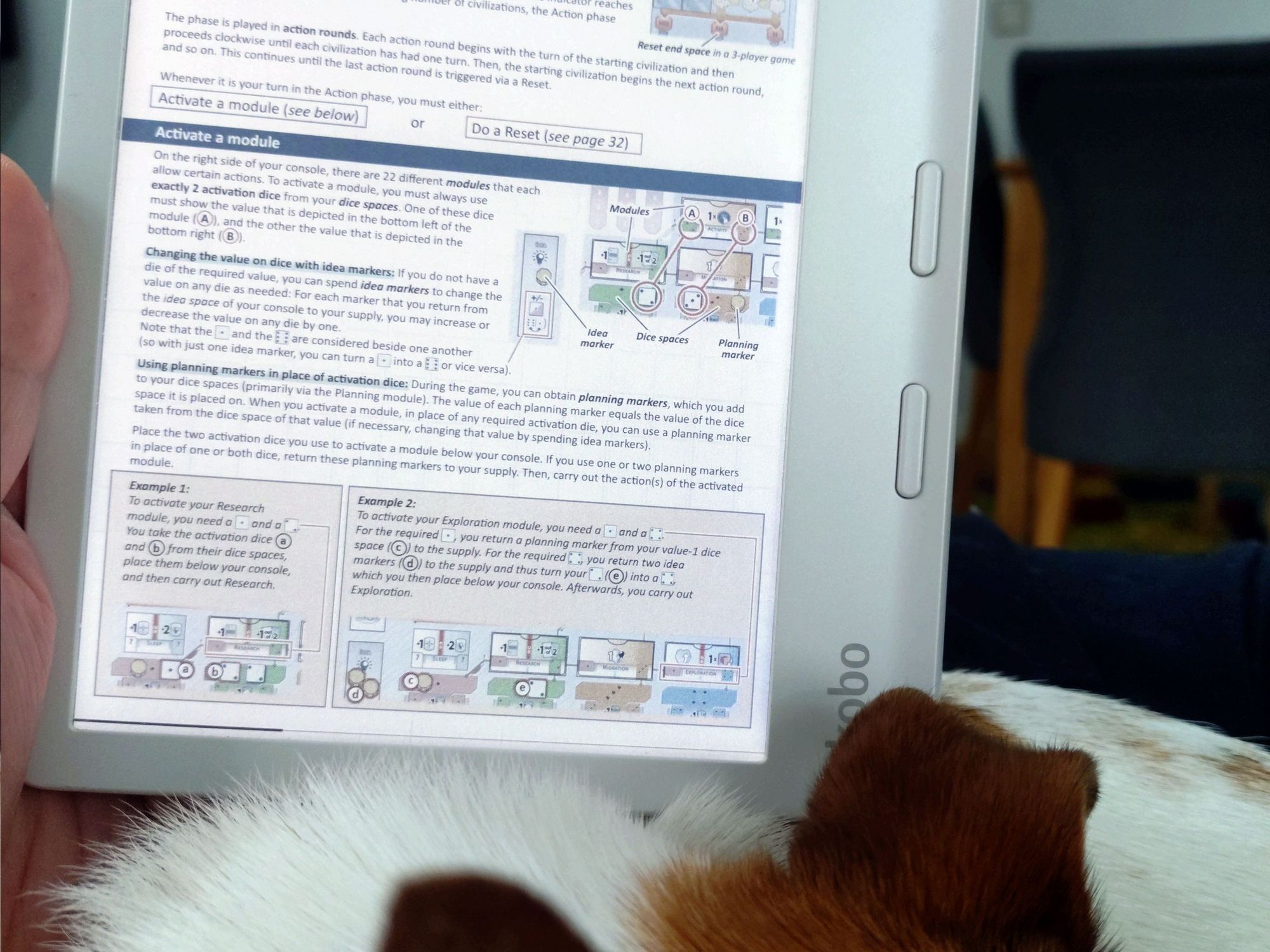 Kobo libre colour displaying the rulebook for Civolution, held above a napping Jack Russel Terrier