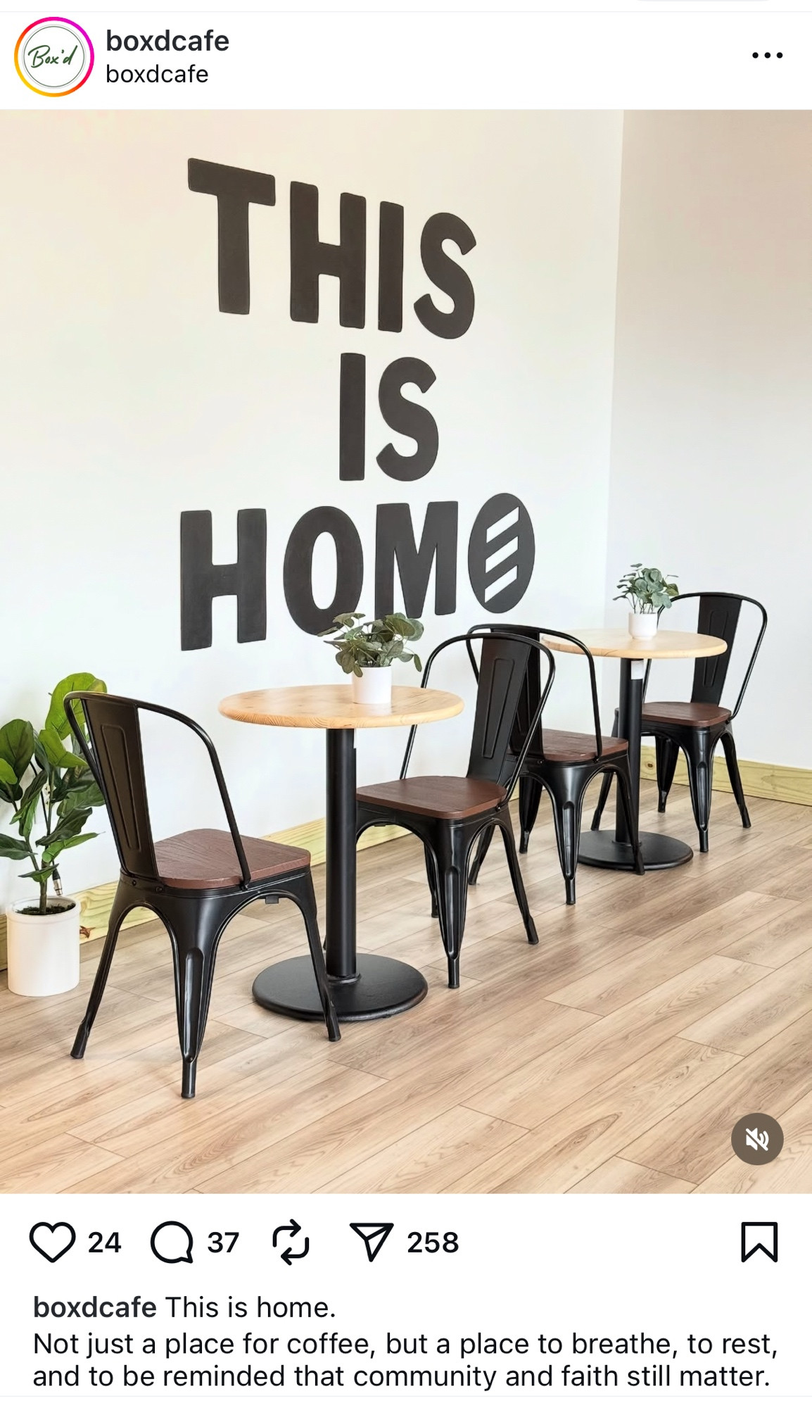 cafe with white wall, painted in large black letters: THIS IS HOME but the font makes it look like it says THIS IS HOMO 