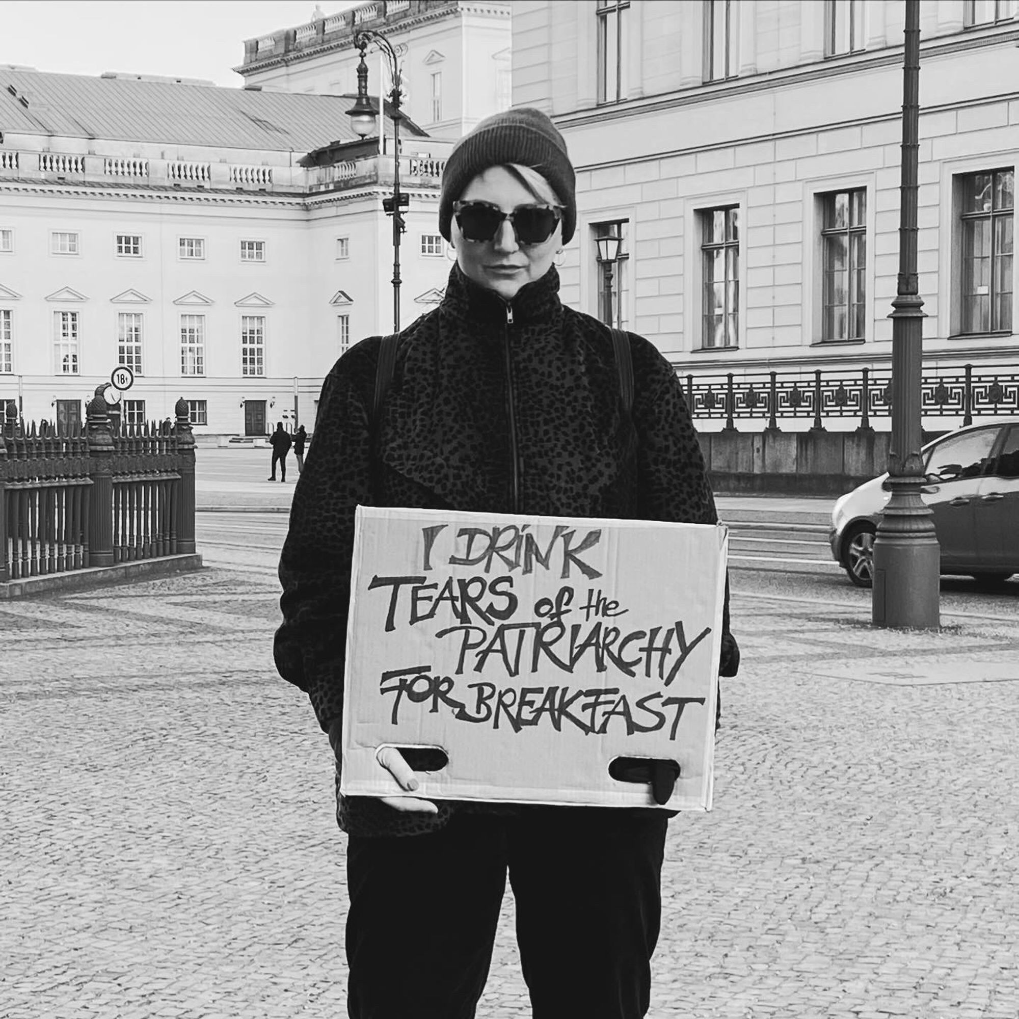 Woman holding a sign saying: I drink tears of the patriarchy for breakfast.