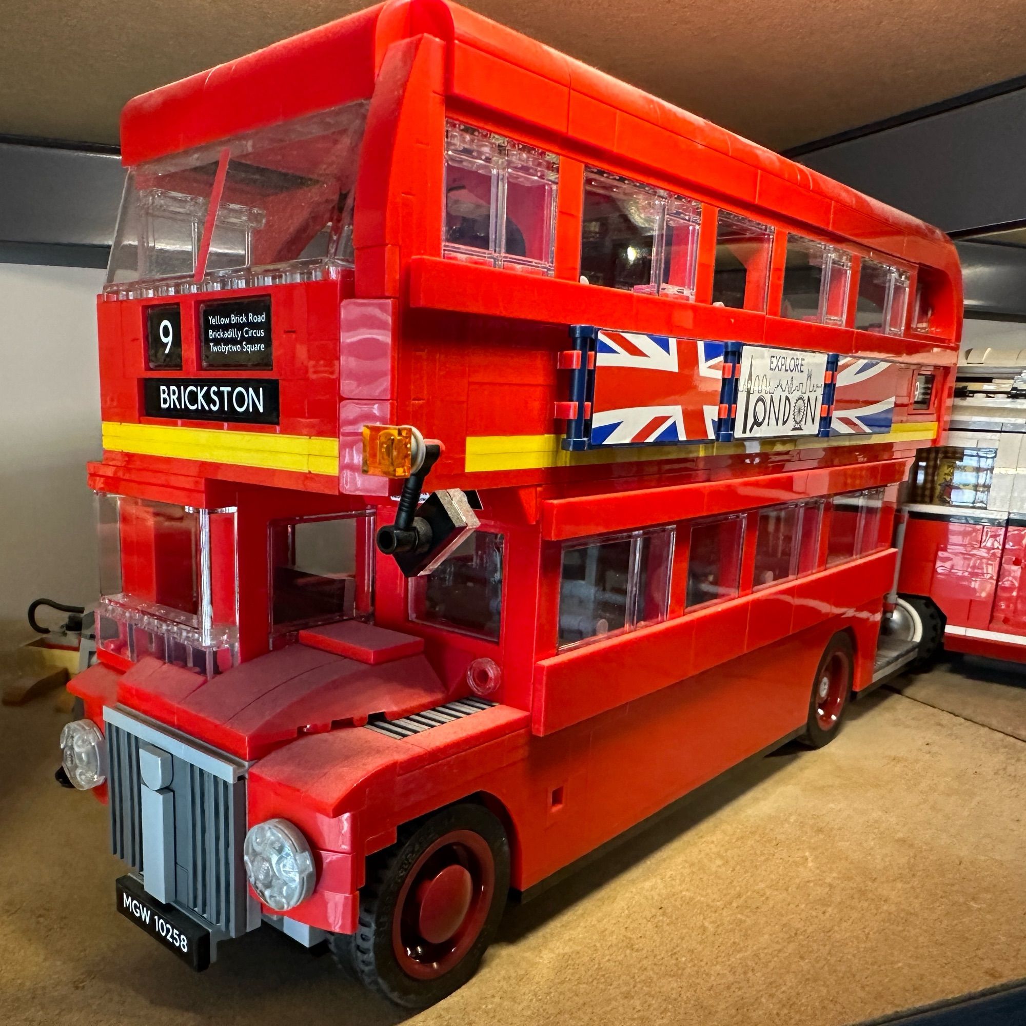 A large (dusty) Lego model of a red old style London bus with the destination “Brickston” on route number 9.