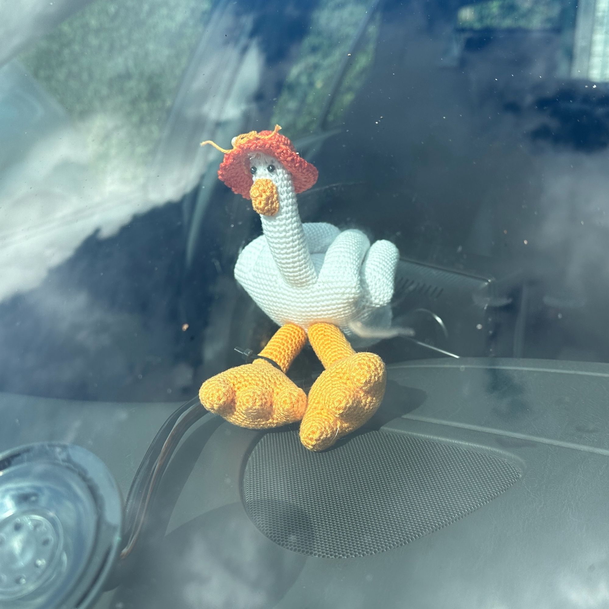 A crochet duck you duck behind the windscreen of my car, zip tied to the CarPlay screen.