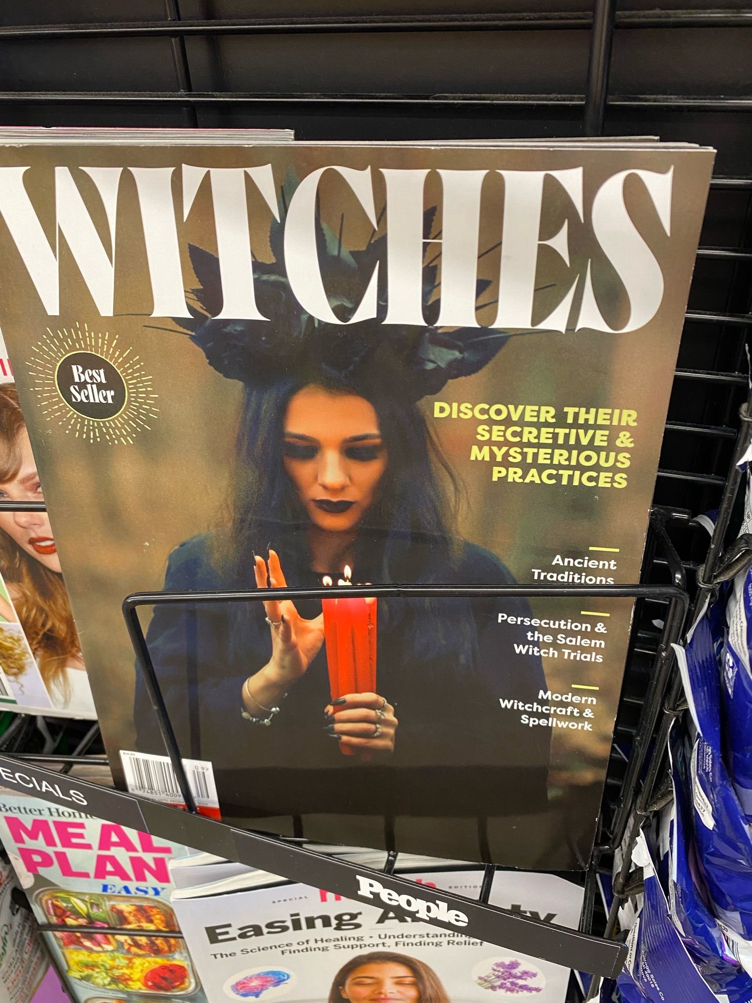 Grocery store checkout stand magazine display of:

WITCHES
Best
Seller
DISCOVER THEIR SECRETIVE & MYSTERIOUS
PRACTICES
Ancient
Traditions
Persecution & the Salem
Witch Trials
Modern
Witchcraft & Spellwork