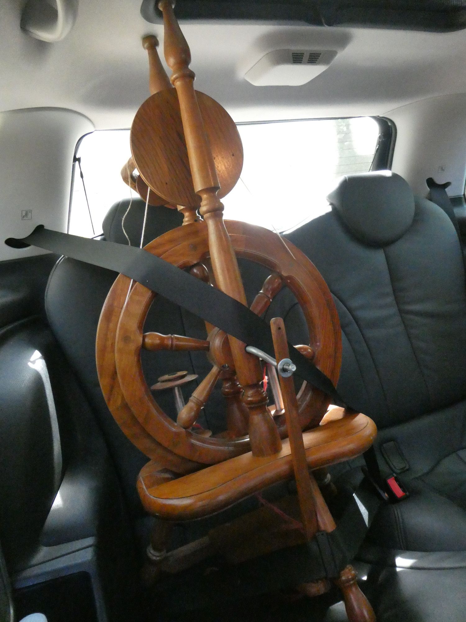 A spinning wheel strapped into the backseat of a car.