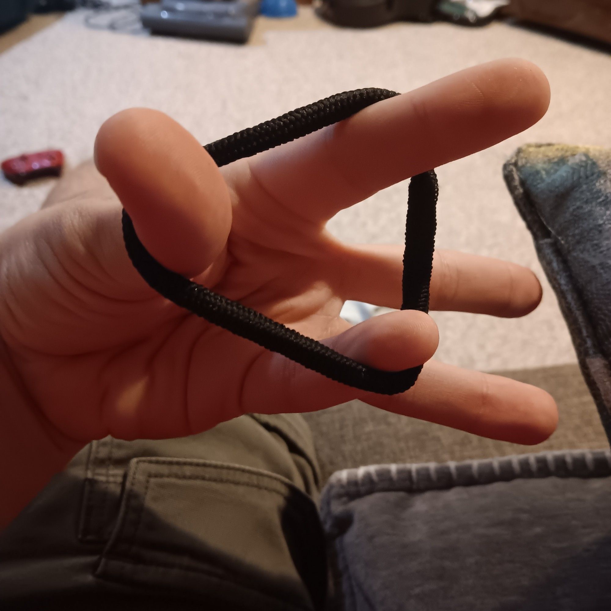 my hand, with three of my fingers holding a hair tie taught in a triangle shape. doing this, however, has contorted my hand strangely. of particular note, some of my double-jointed fingers bend backwards farther than the average hand, and my hitchiker's thumb is clearly visible.