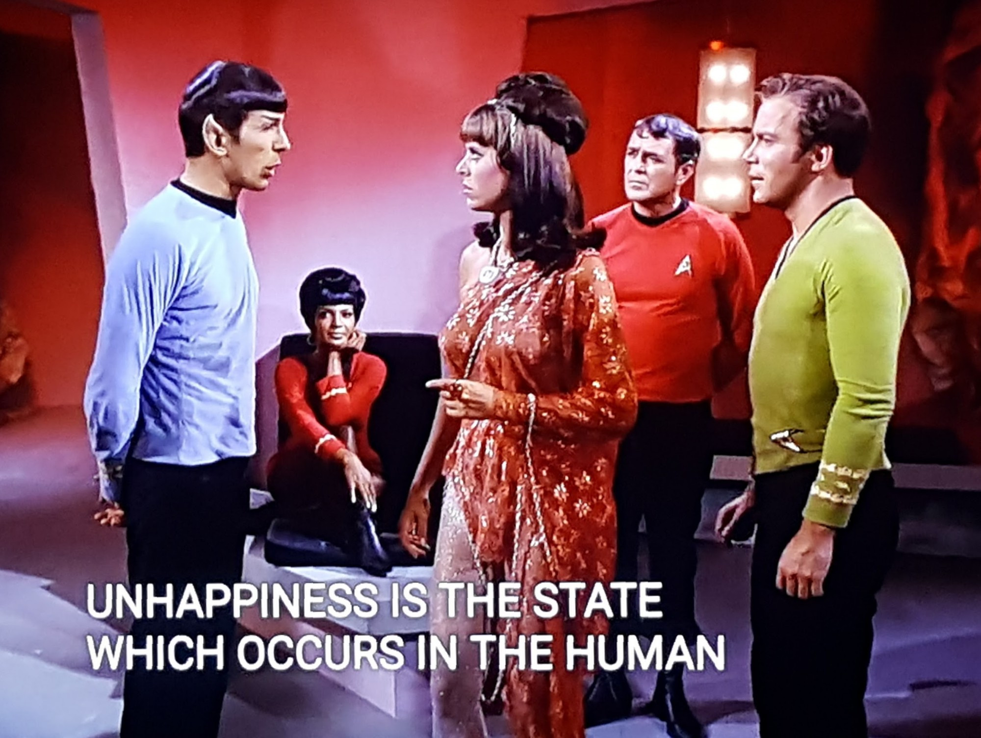 TOS scene. We're on an away mission and we're in a room lit in RED. Uhura is sitting on a chair in the background, chin on hand, listening intently like she's watching one of those dumb shows on TV where people get married after knowing each other for 10 minutes. Up closer to us is Kirk and Scotty standing and looking at Spock who is talking to a human looking lady in a badass 70s red/orange dress with some glittery elements to it. She has a massive hair bun also. Like a whole ball of hair on top of her normal hair. Closed caption reads, "Unhappiness is the state which occurs in the human"