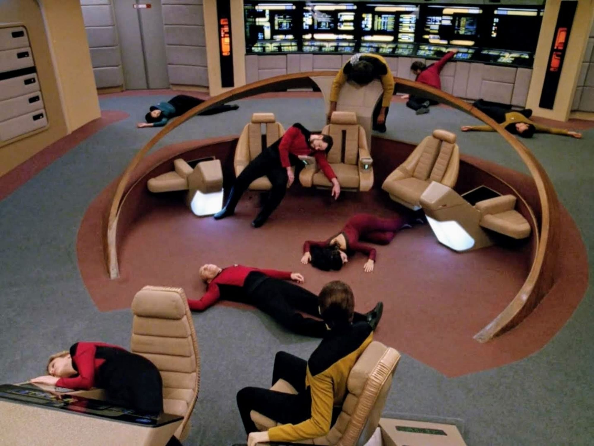 The bridge of the Enterprise is shown from above looking down. Data sits at his console looking back at the rest of the crew, who are all passed out in various situations; on the floor, slumped over a console, or half falling off their chairs. Worf, notorious Klingon warrior, dangles over the tactical station.