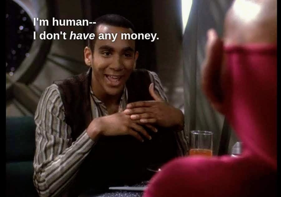 DS9 scene. Jake Sisko is sitting facing us at a table on DS9 station. He's having a chat with Nog, a young ferengi with giant ear lobes. Nog is in Starfleet uniform and facing away from us. Jake is wearing normal guy space clothes. Jake looks animated and talking with hand gestures. Closed caption reads, "I'm human--I don't *have* any money."
('Have' is in italics)